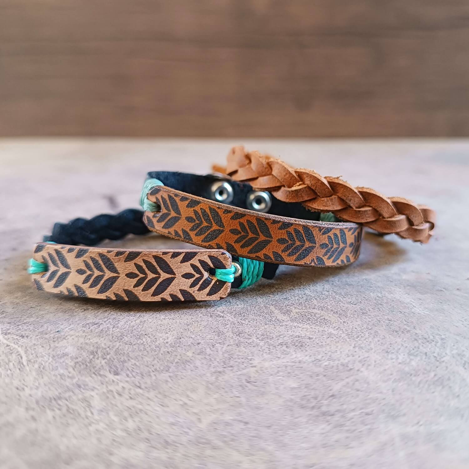 Three leather bracelets set with braided design on a wooden surface