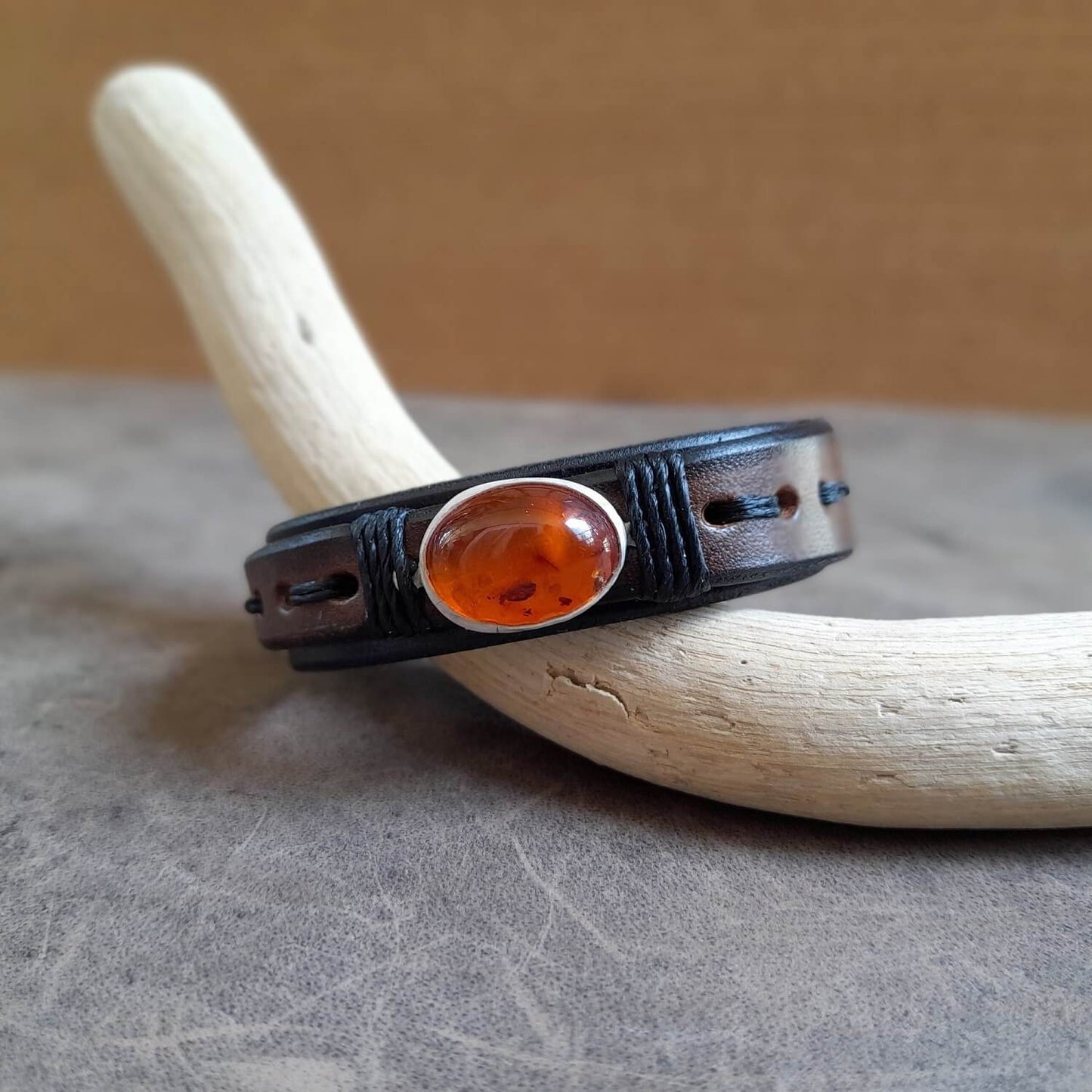 Detailed close-up of the oval natural amber pendant on the Amber Time Capsule Bracelet, highlighting its smooth texture, deep orange hues, and unique inclusions.