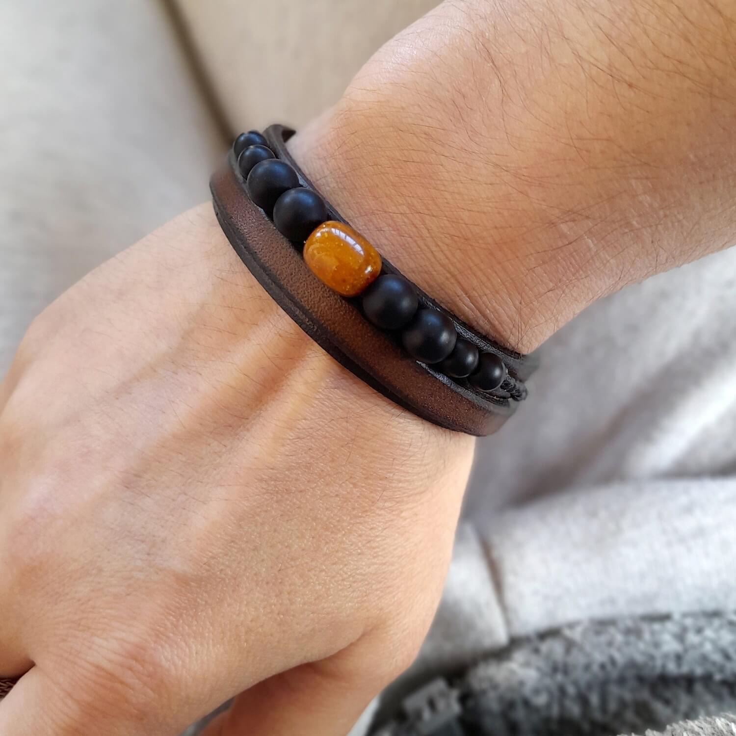 Men's Amber and Onyx leather bracelet worn on a wrist, showcasing fit and stacked look.