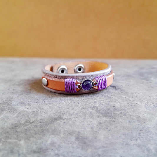 Close-up of the natural Amethyst stone on the Amethyst & Leather bracelet, showing its purple color and the purple beeswax thread detail.