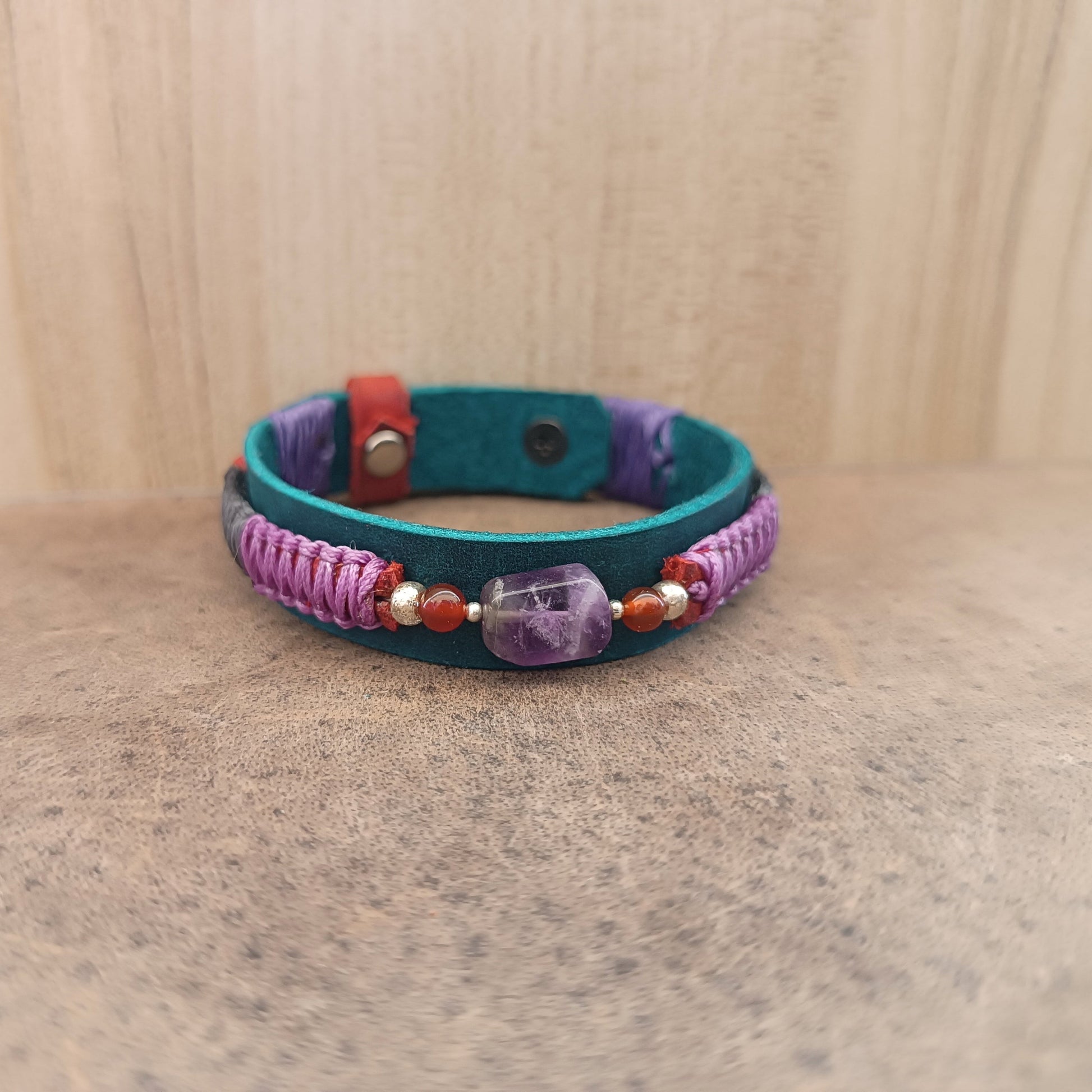 Amethyst gemstone bracelet with purple and grey braid – front view on leather surface