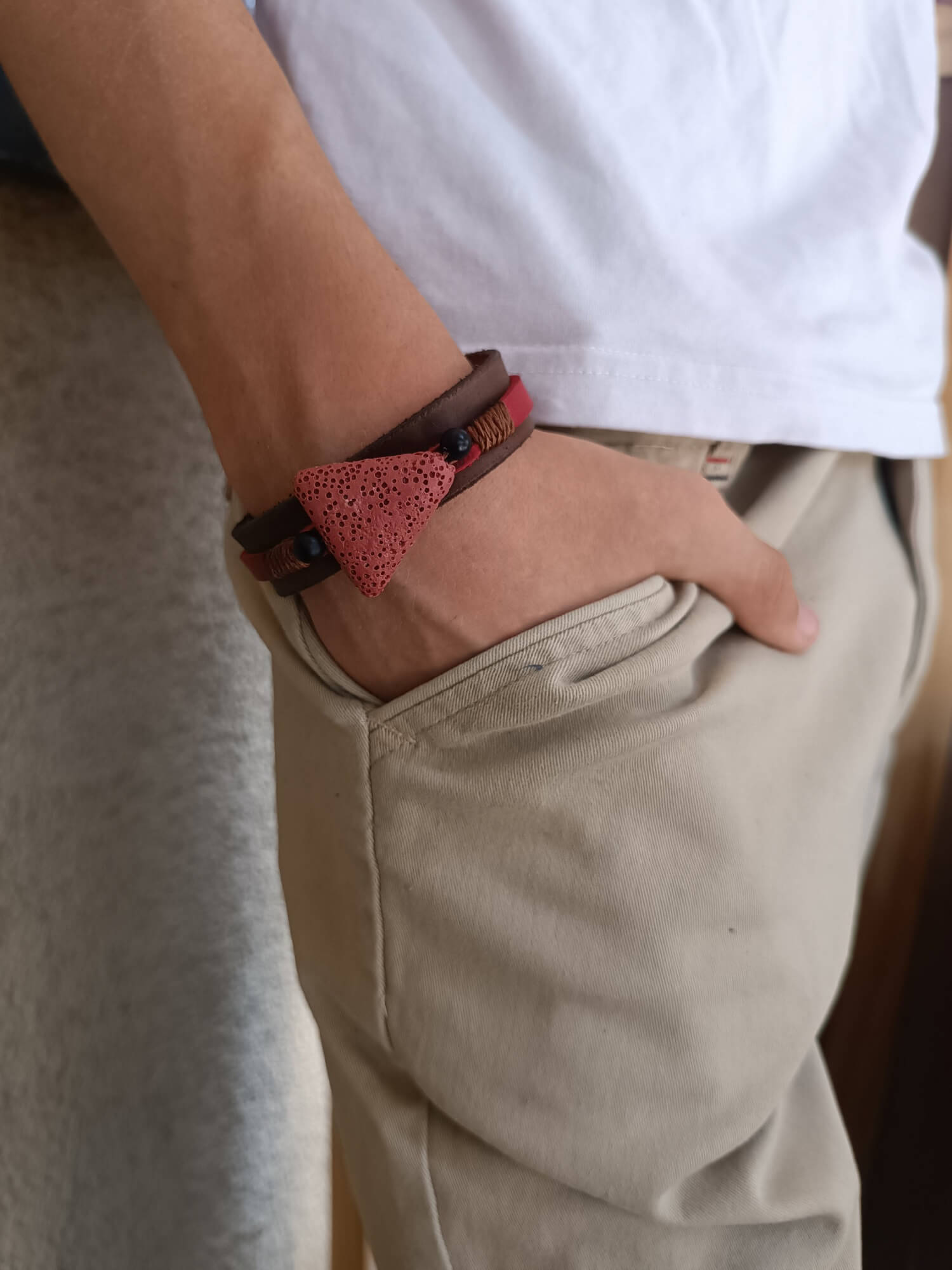 The Earth's Pulse Aromatherapy Bracelet worn on a wrist, showcasing its layered design, dark brown leather, and the prominent red lava bead, complementing a relaxed, mindful style.