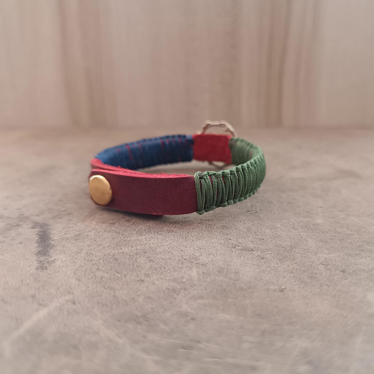 Back view of The Guardian's Balance Trident Bracelet, displaying the gold stainless steel snap button closure and the adjustable settings on the red leather band.