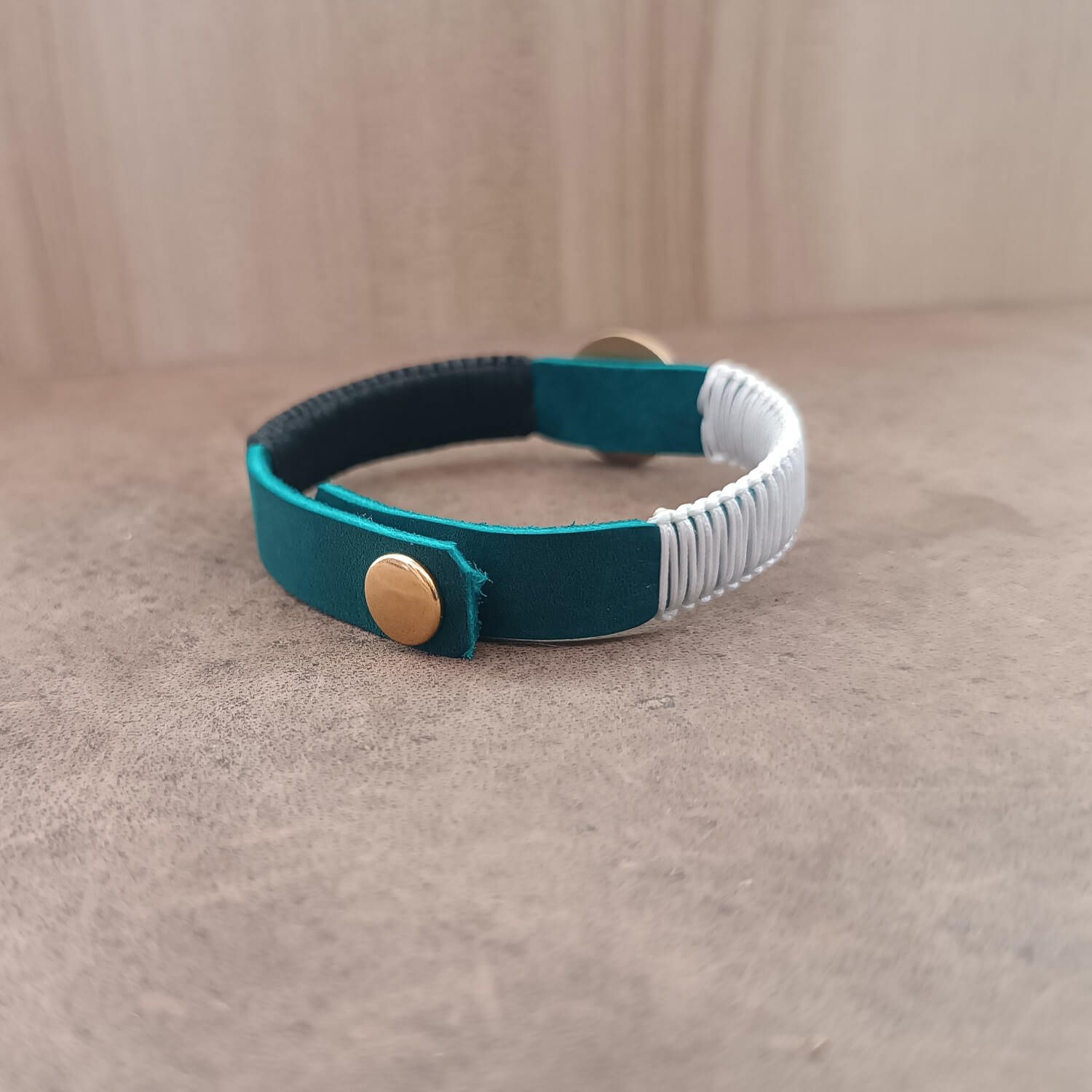 Back view of The Instinctive Shield Wolf Bracelet, displaying the gold stainless steel snap button closure and the adjustable settings on the blue leather band.