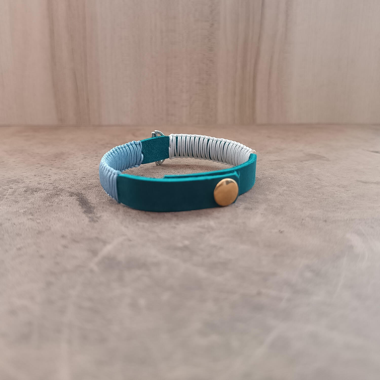 Back view of The Lotus's Serenity Bracelet, displaying the gold stainless steel snap button closure and the adjustable settings on the blue leather band.