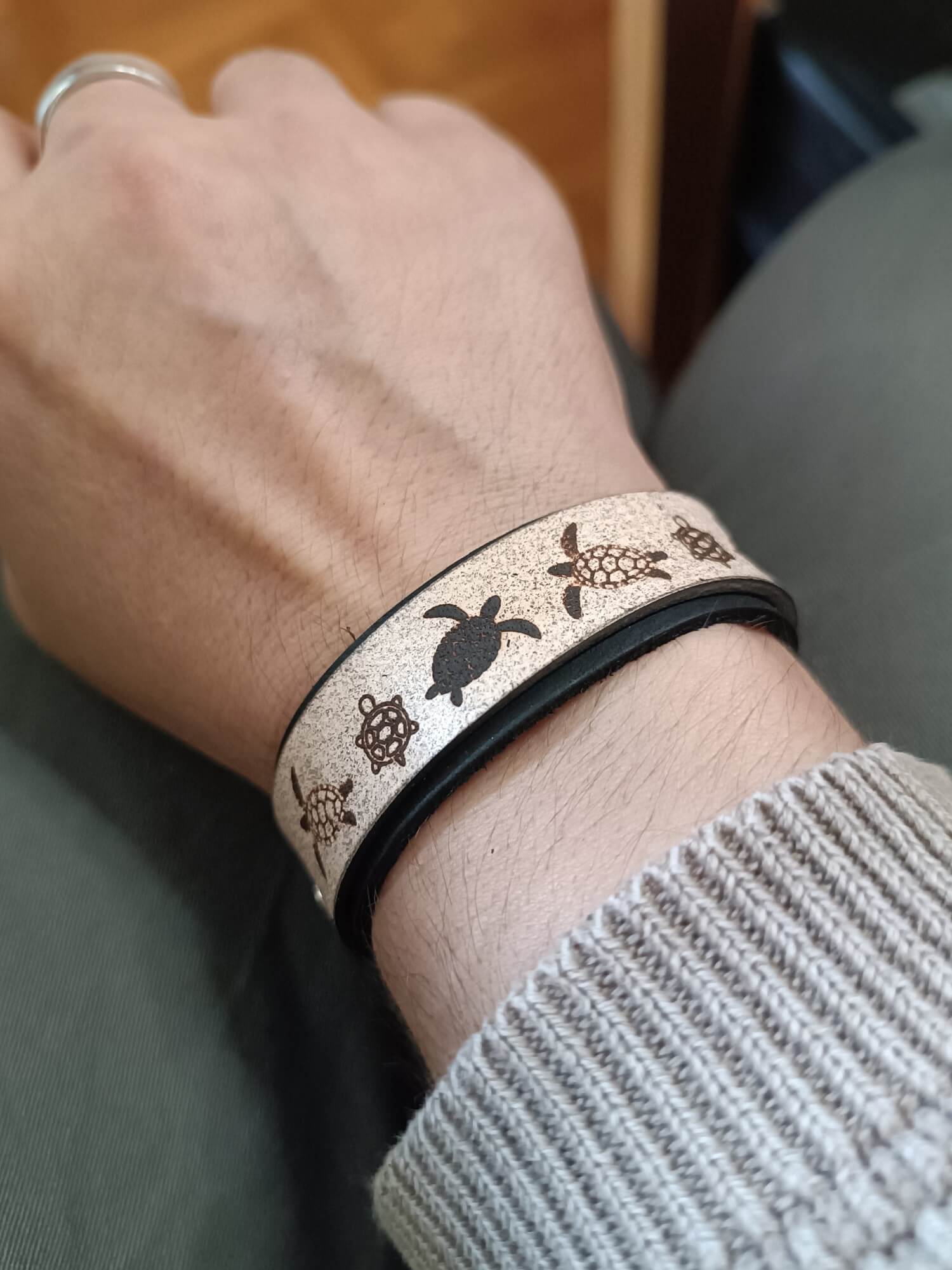 Black Tortoise Bracelet worn on wrist showing contrasting leather layers and engraving