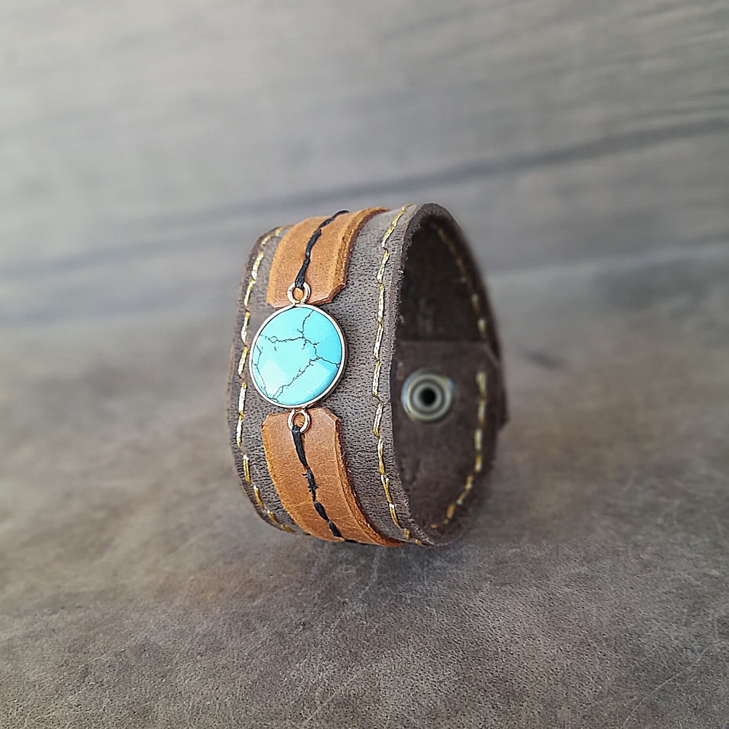 Brown leather bracelet with turquoise stone on a gray surface