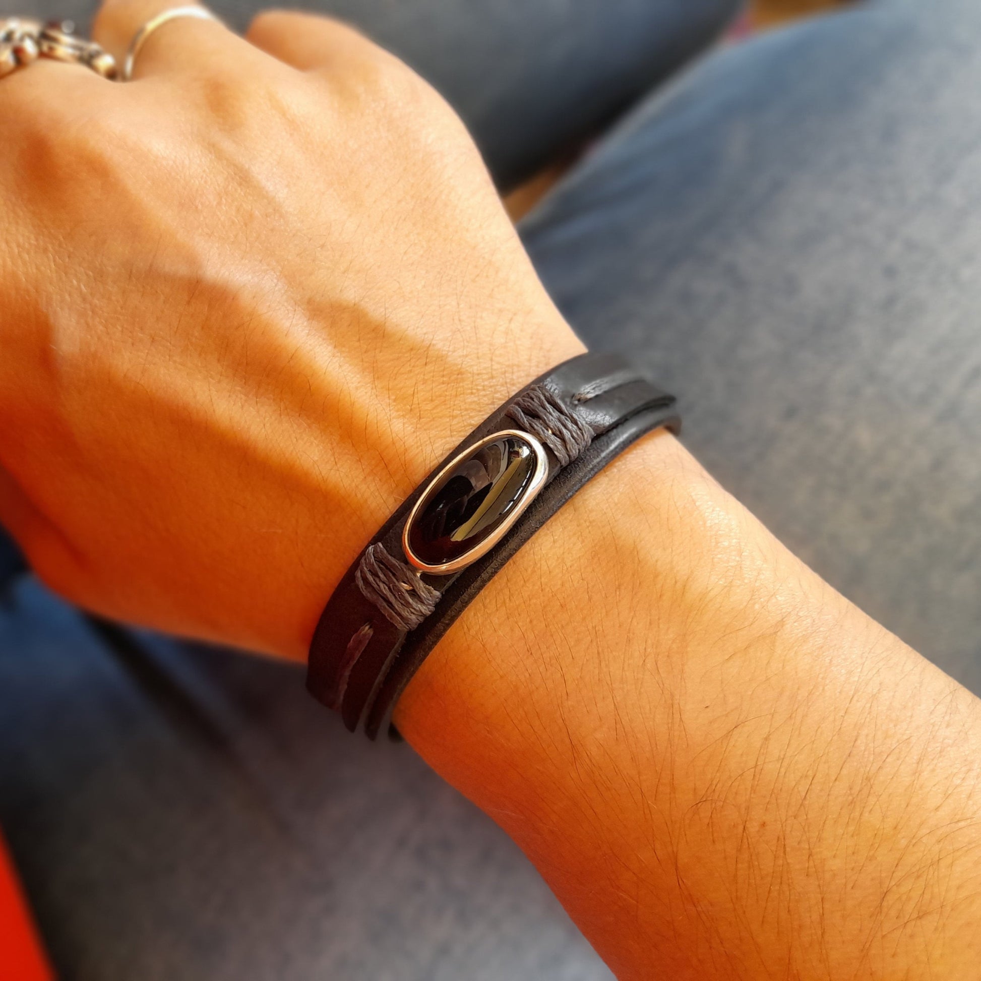 The Minimalist Black Obsidian Leather Bracelet worn on a wrist, demonstrating its comfortable fit, slender design, and elegant look.