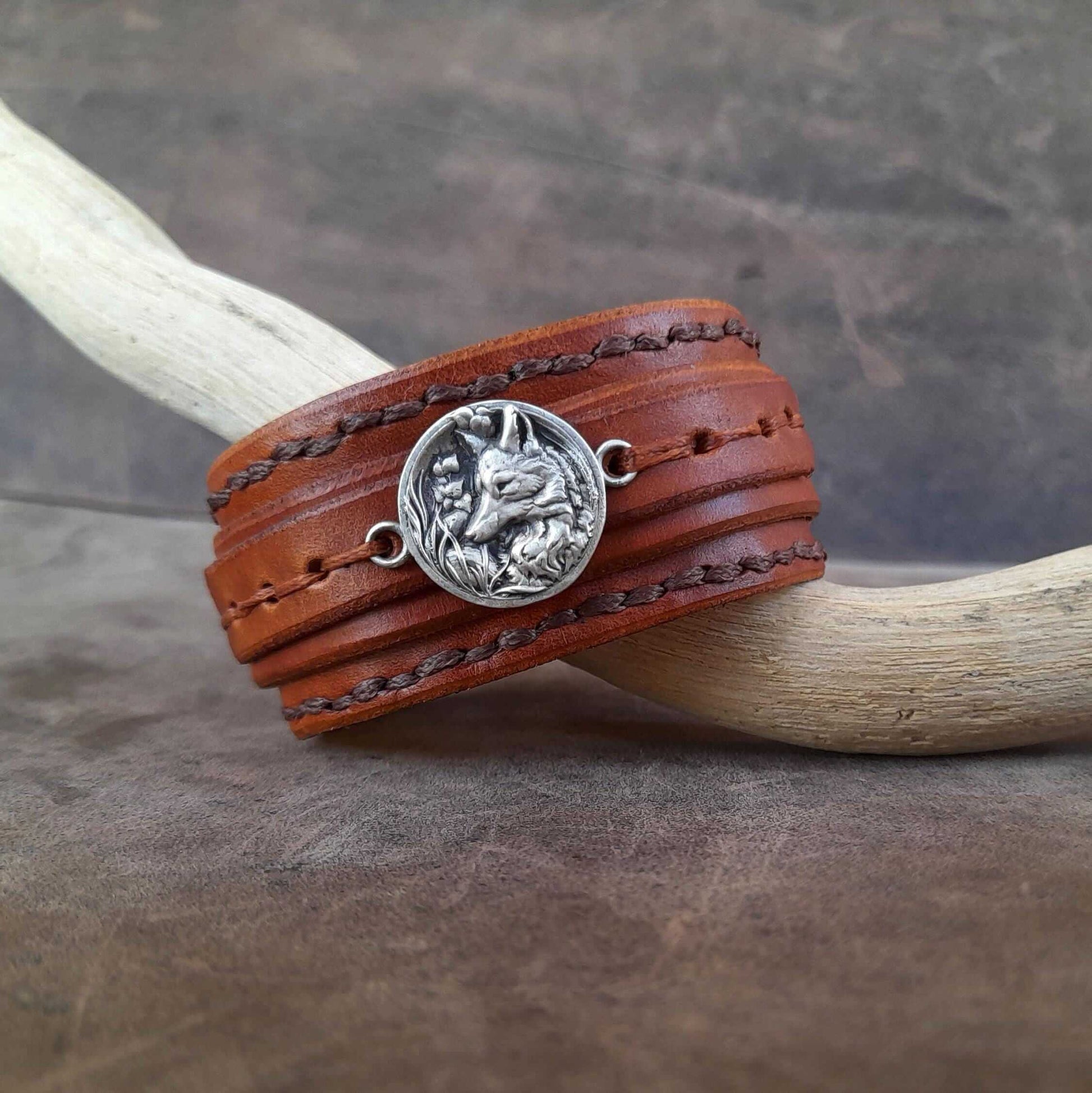 Brown leather wrap bracelet with silver fox pendant on a wooden stick