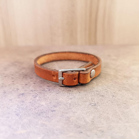 Brown leather bracelet with a silver buckle on a textured surface
