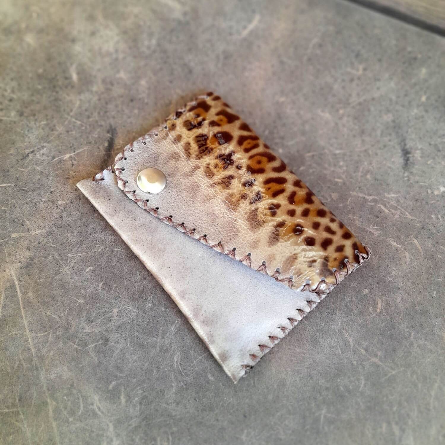 Detailed close-up of the glossy leopard print leather on the wallet, highlighting its sheen and pattern.