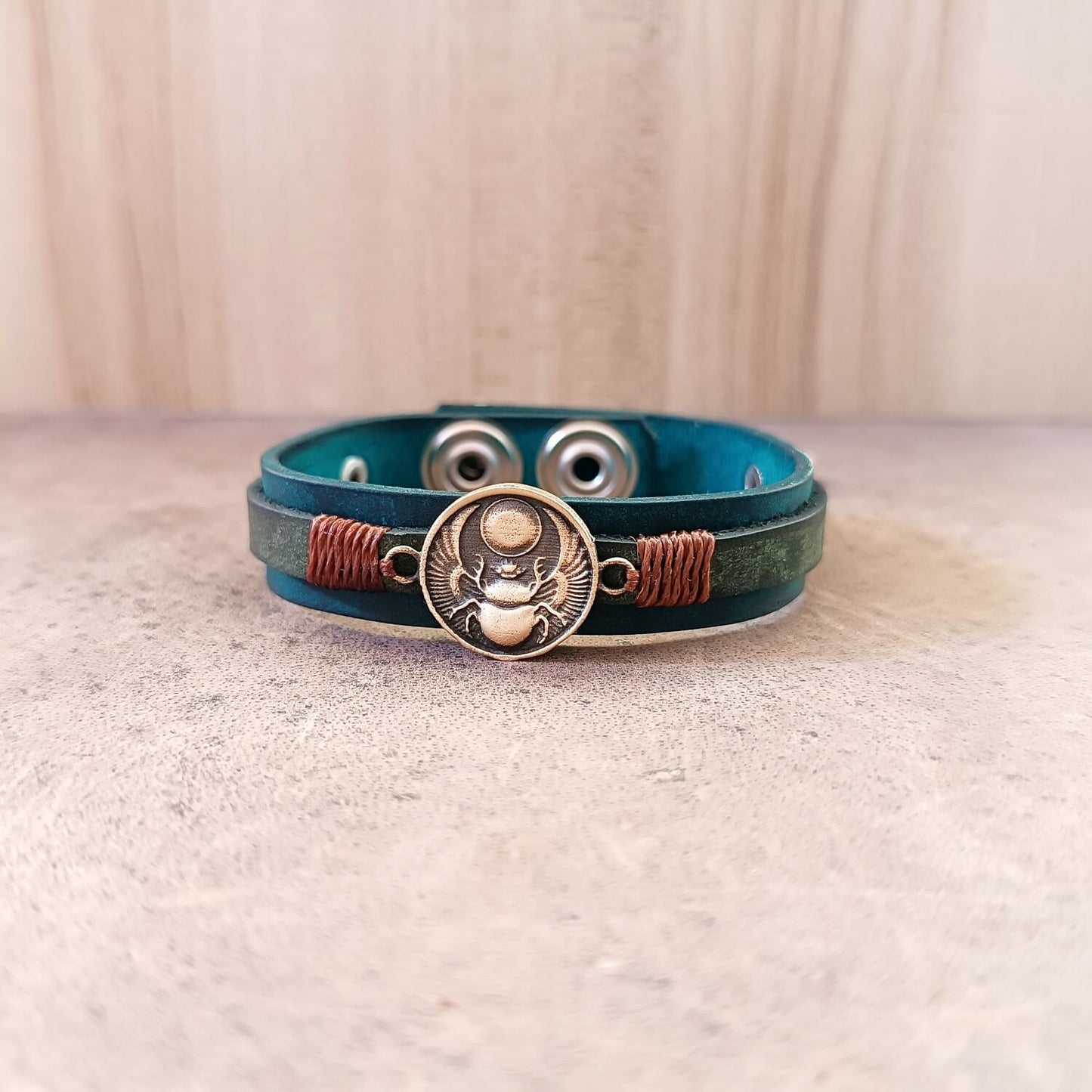 Close-up front view of Solar Scarab Bracelet, focusing on the detailed handcrafted oxidized brass scarab pendant with spread wings and sun motif.