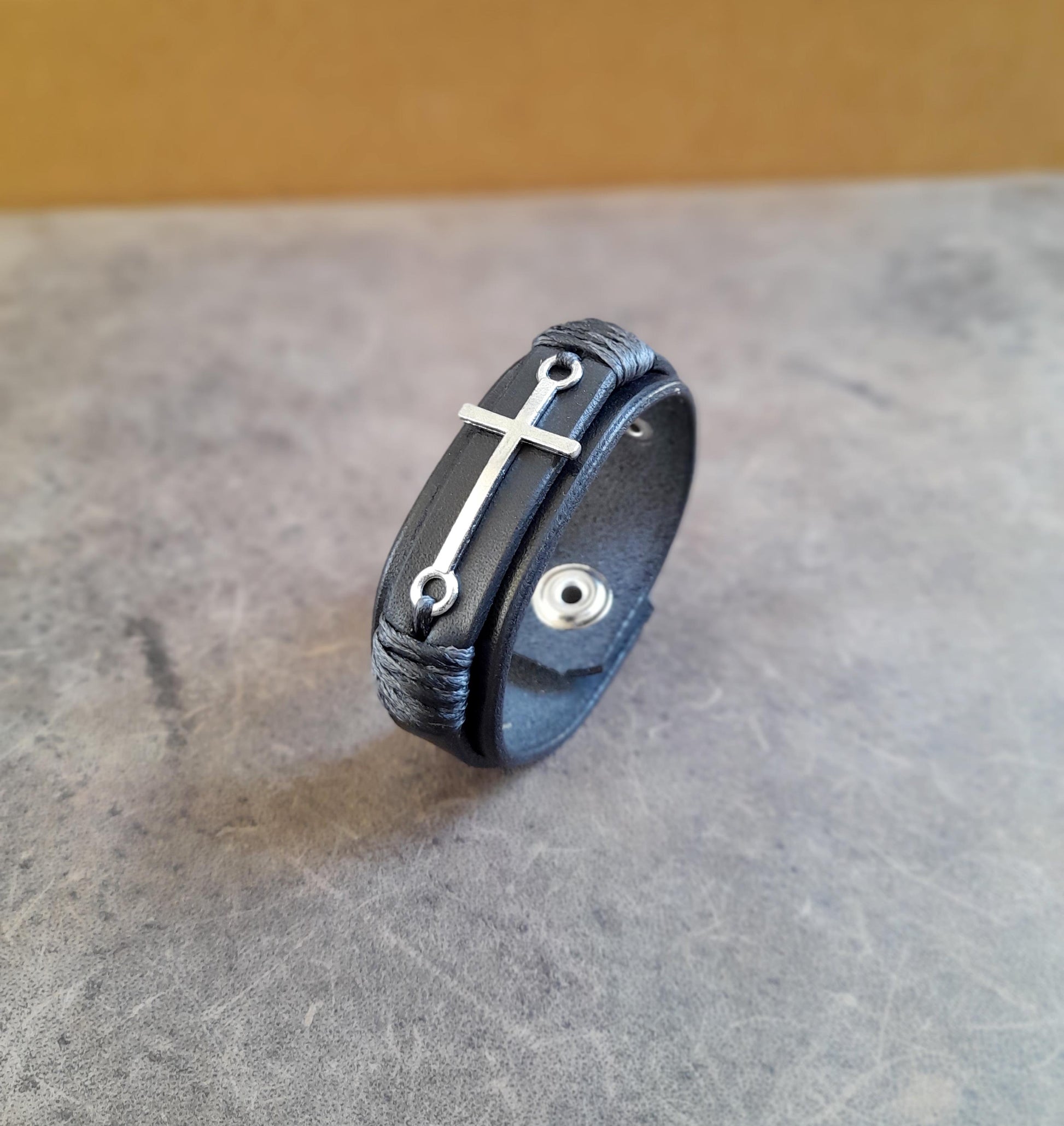 Close-up of The Steadfast Spirit Cross Bracelet, highlighting the polished stainless steel silver cross and the rich texture of the full-grain leather.