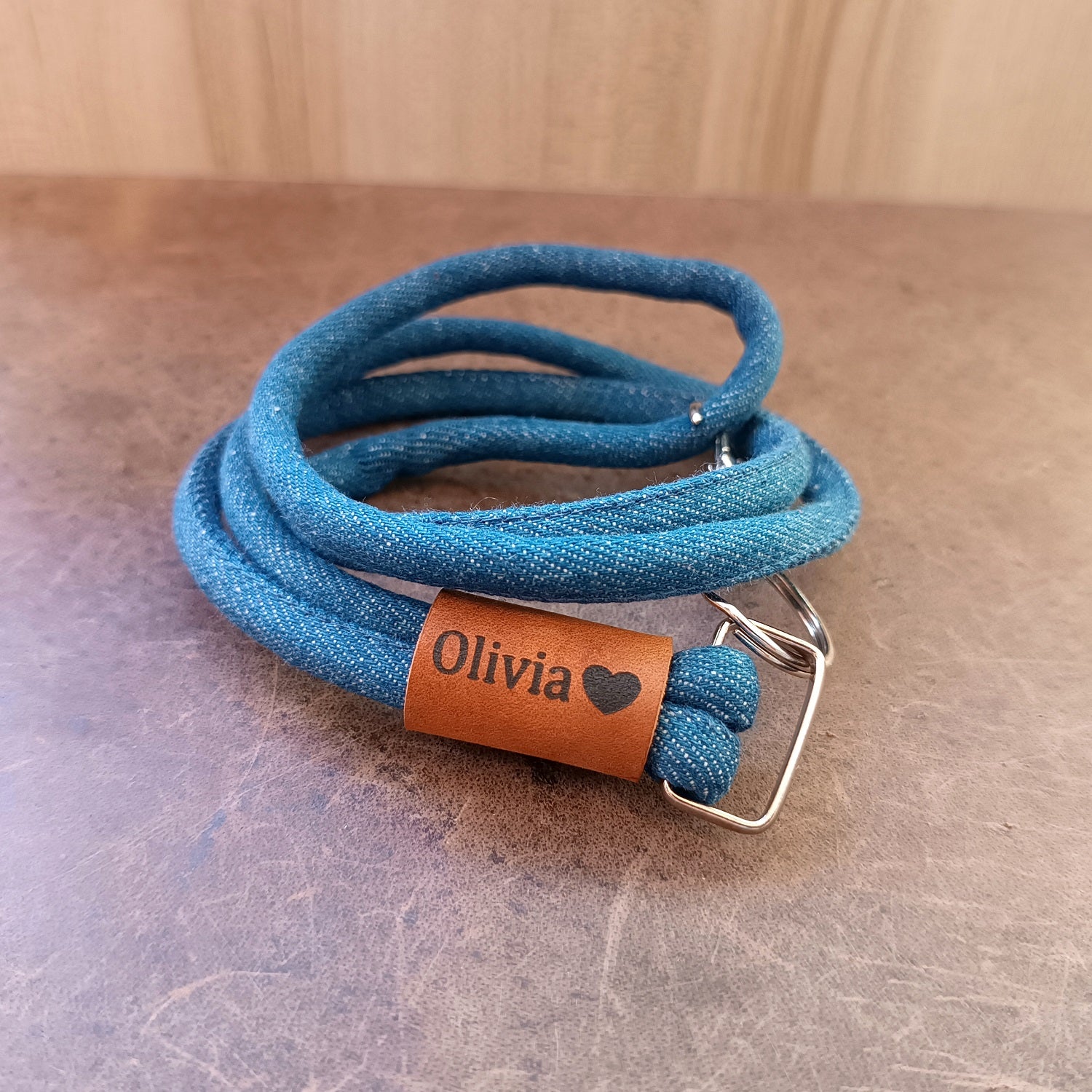 Close-up of the Crazy Horse leather accent on the Personalized Denim & Leather Lanyard, clearly showing a custom laser engraving and the metal D-ring and clasp.