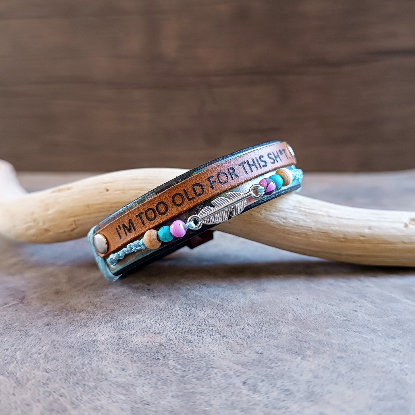 Close-up showing the unique hand-dyed colorful pattern of the No BS wrap bracelet leather band and the vibrant details of the colorful beads and silver-tone feather charm.