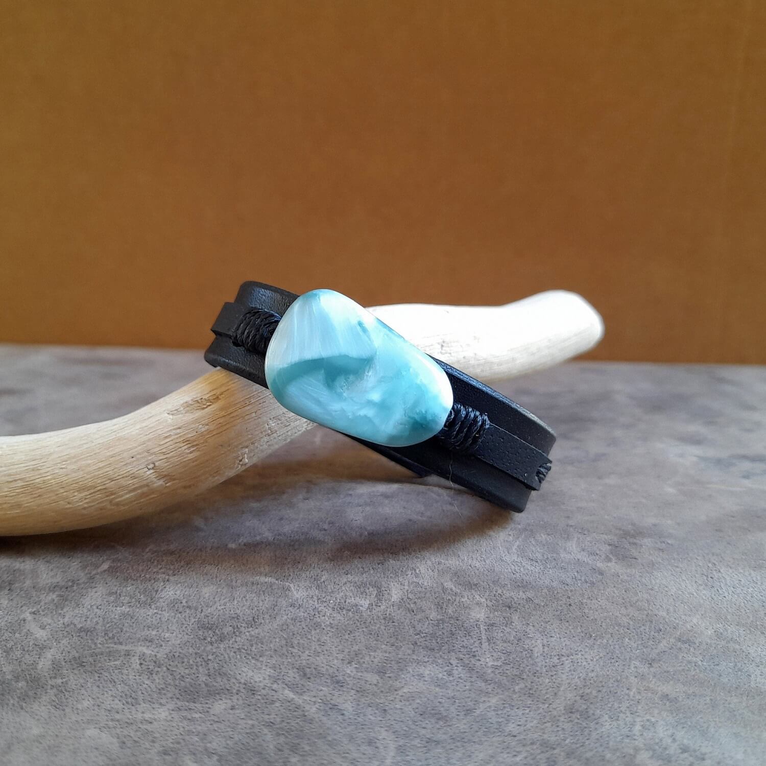 Close-up showing the black oiled full-grain Vachetta leather of the base band and the narrower top layer, emphasizing the material texture and layered design.