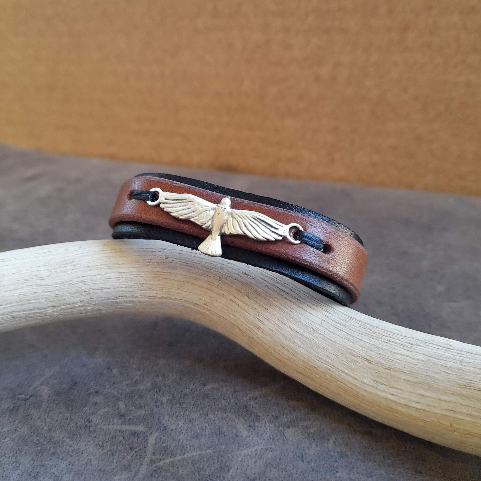 Brown leather bracelet with eagle emblem on a wooden surface