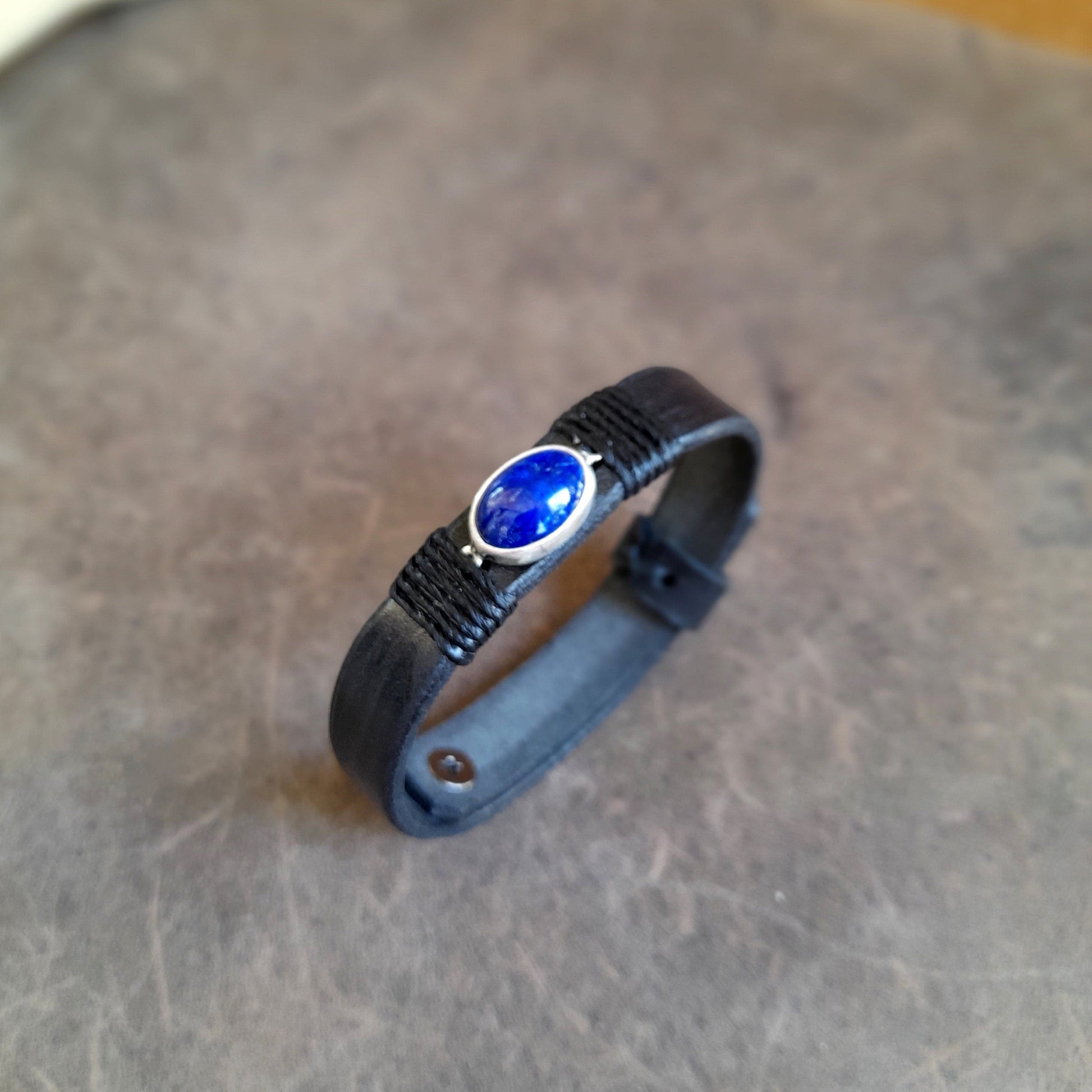 Close up side view of The OOAK Sodalite Clarity Bracelet: A sleek black full-grain leather single-band bracelet featuring an oval natural sodalite stone on a sterling silver pendant, wrapped with black cord.
