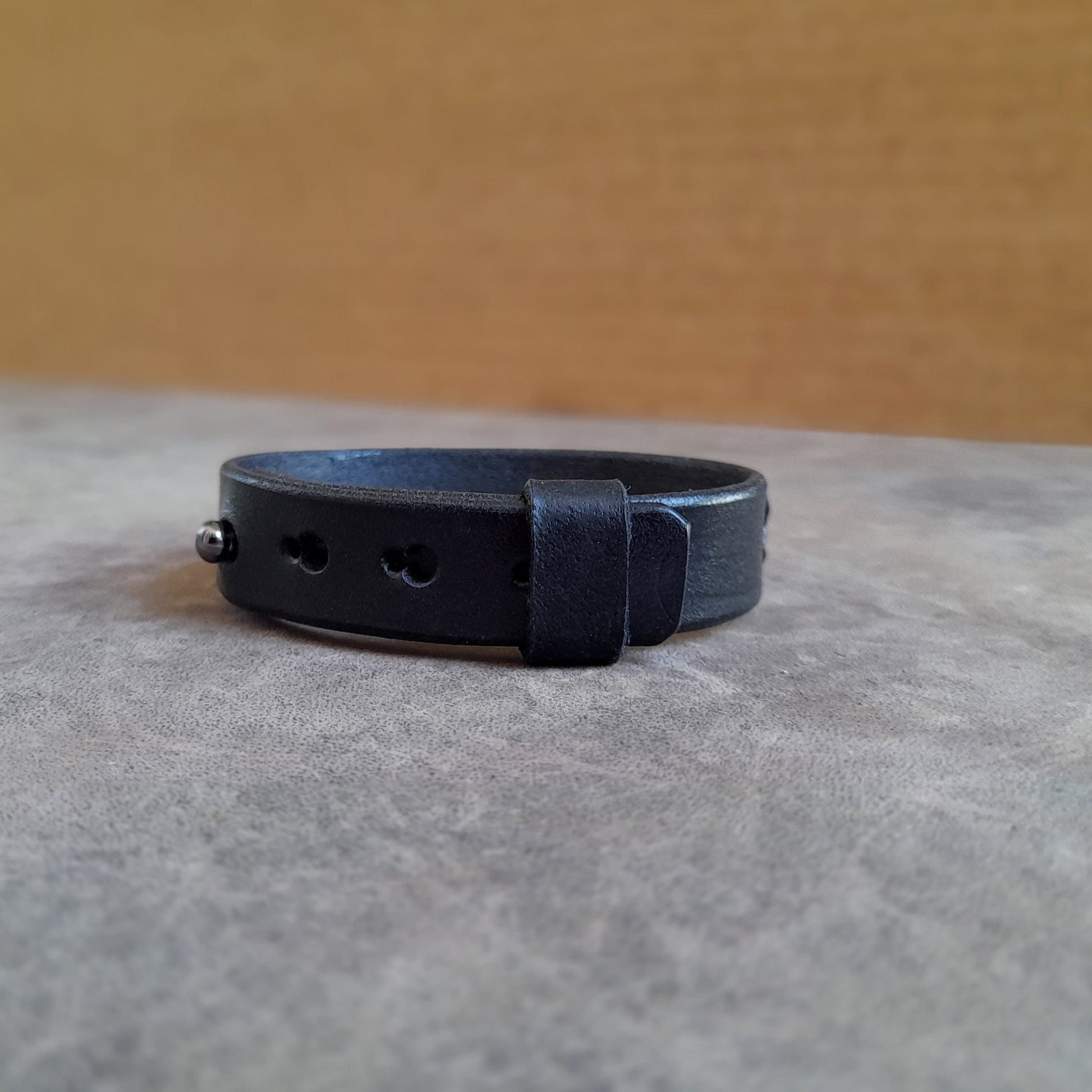 Close-up of the gun metal stud button closure on the Minimalist Black Obsidian Leather Bracelet, showing the multiple adjustment openings.