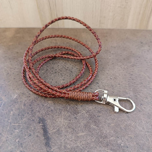 Brown braided leather lanyard with a silver clasp on a gray surface