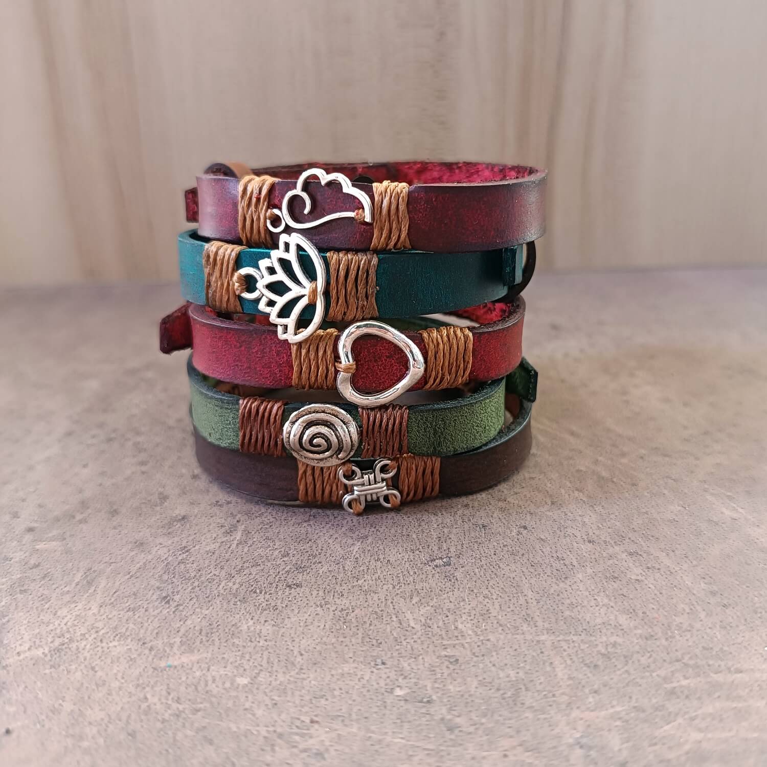 Collection of Inner Anchor Bracelets from Quiet Rebirth Collection, showing all 5 designs: Blue Lotus, Spiral, Red Heart, Phoenix Wing, and Unbroken Chain Link on various colored Crazy Horse leather bands.