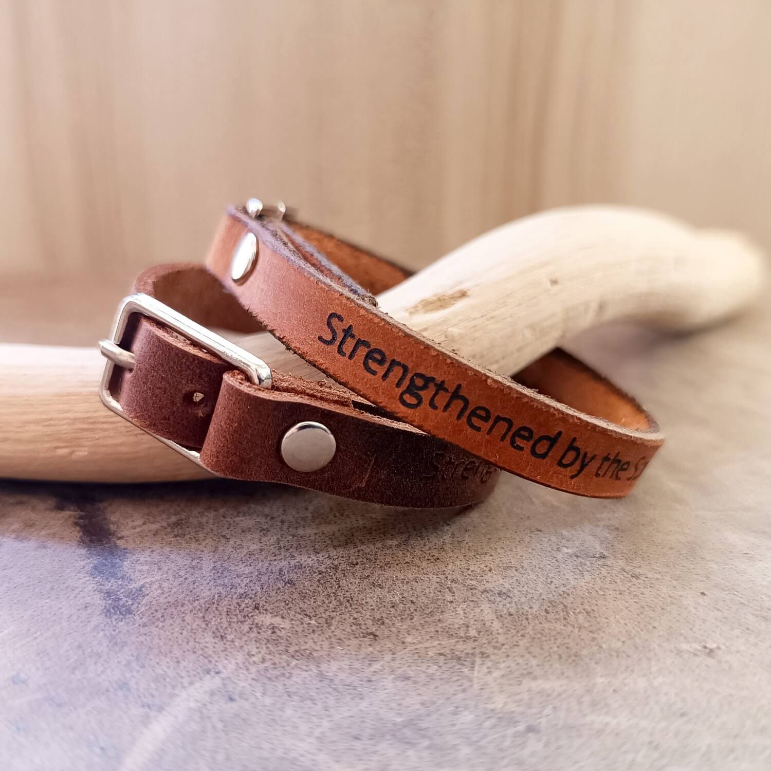 Brown leather bracelets - one dark brown and one warm brown, with engraved text on a textured surface