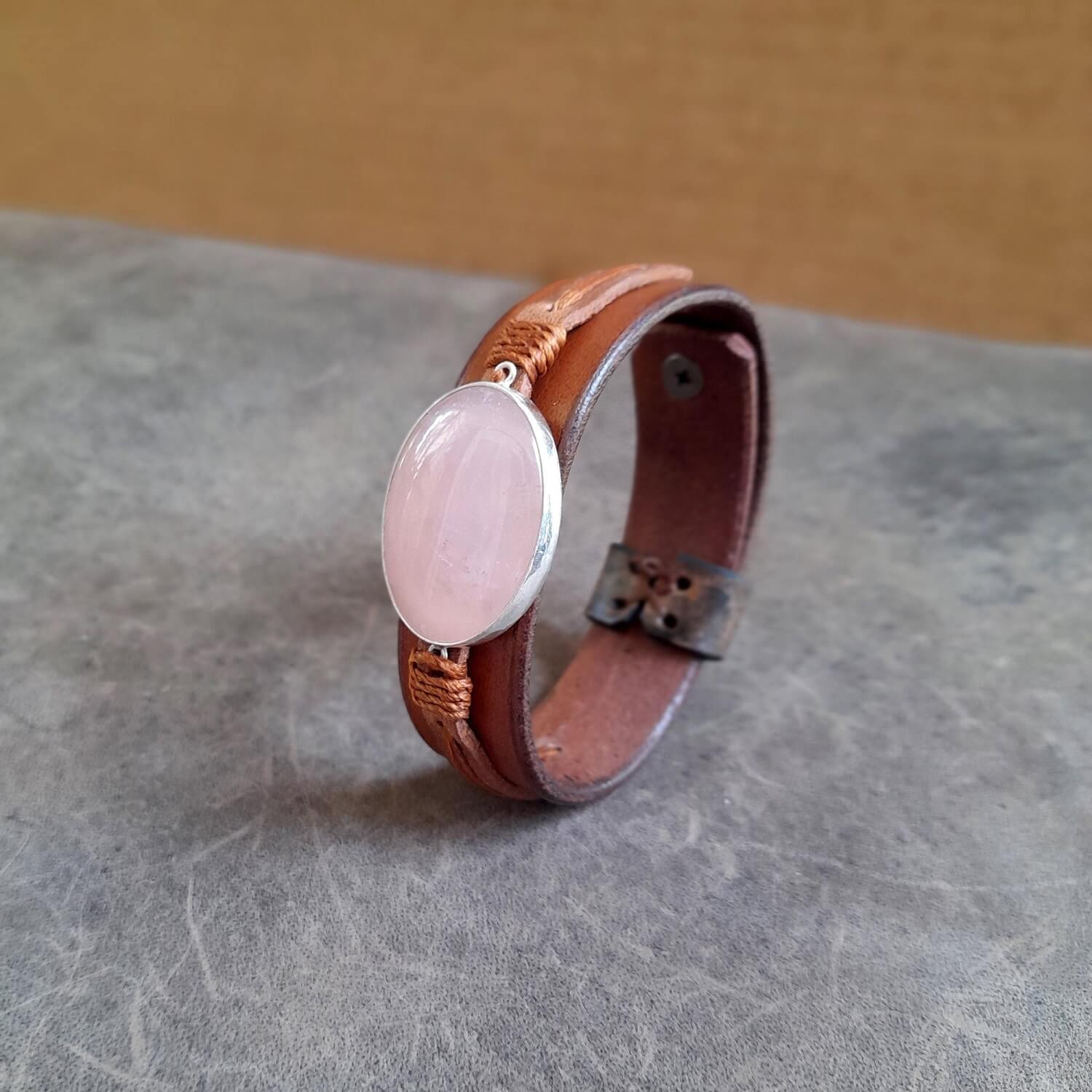 Detailed close-up side view of the large oval natural rose quartz stone on the cuff, highlighting its soft pink hues and sterling silver setting.