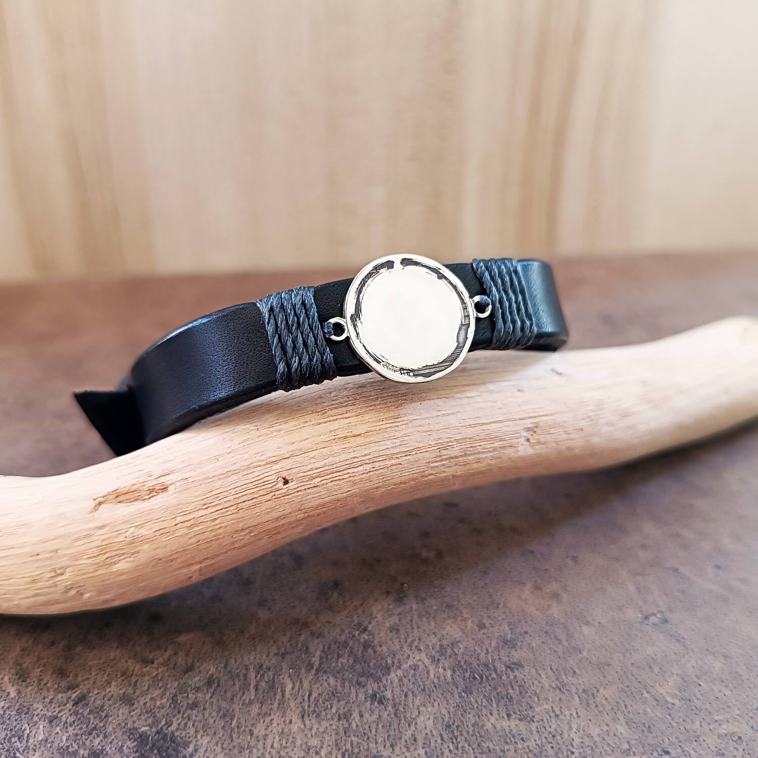 Black leather bracelet with silver Enso Circle on a wooden surface