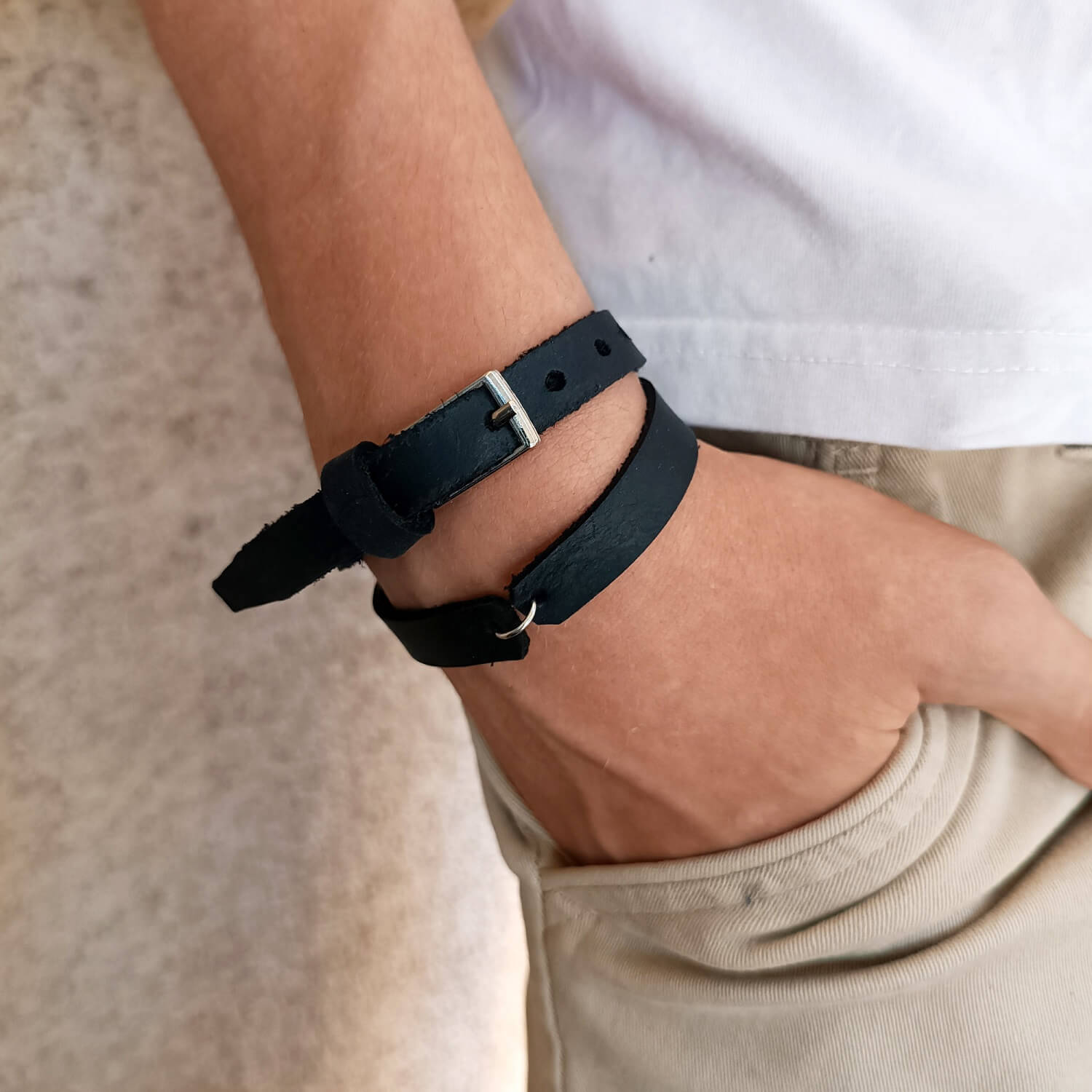 The Evolve Choker/Bracelet worn as a double-wrap bracelet on a man's wrist, showcasing its sleek black Crazy Horse leather and the central stainless steel ring, ready for charms or as minimal centerpiece.