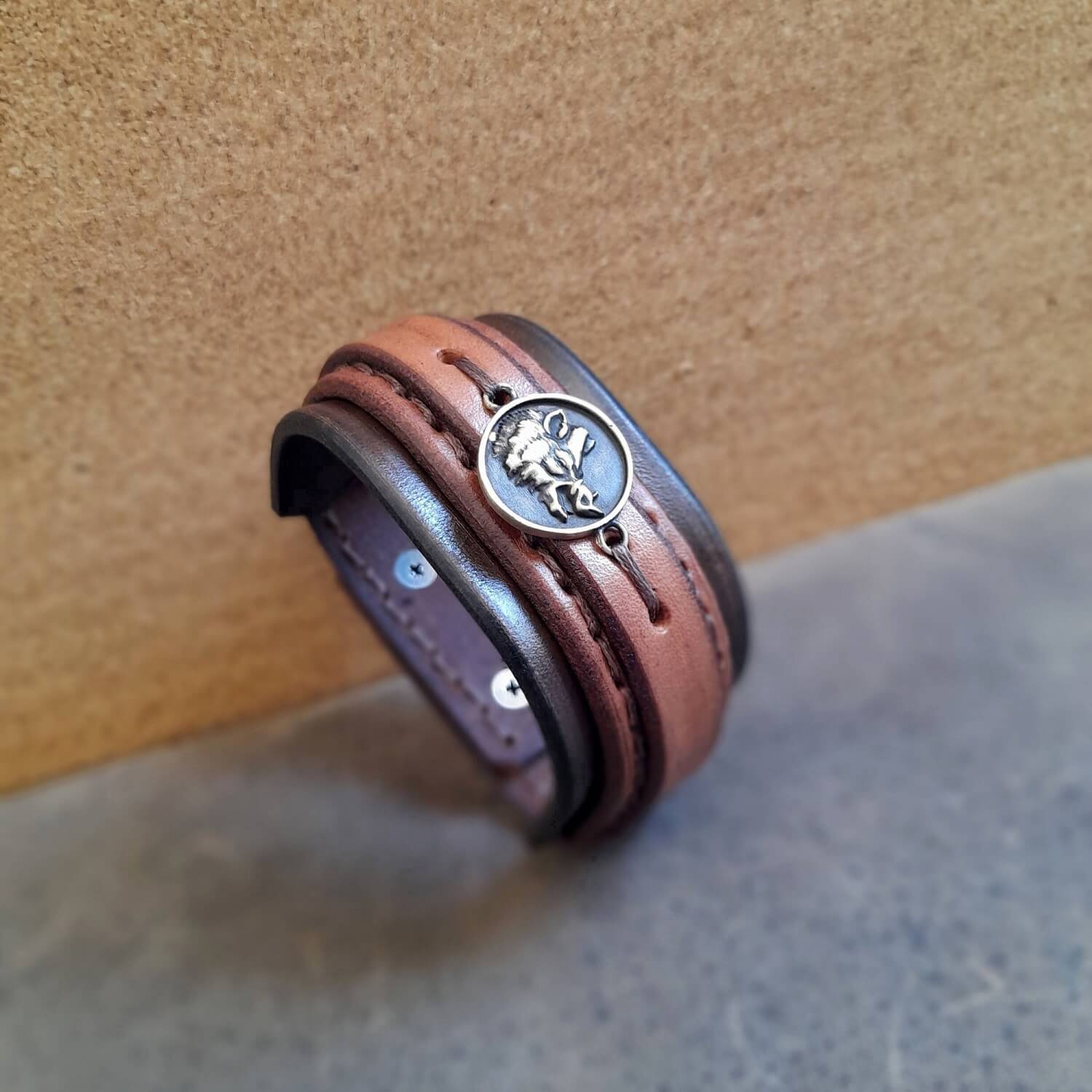 chunky wide leather cuff in three brown layers, featuring a wild boar brass pendant