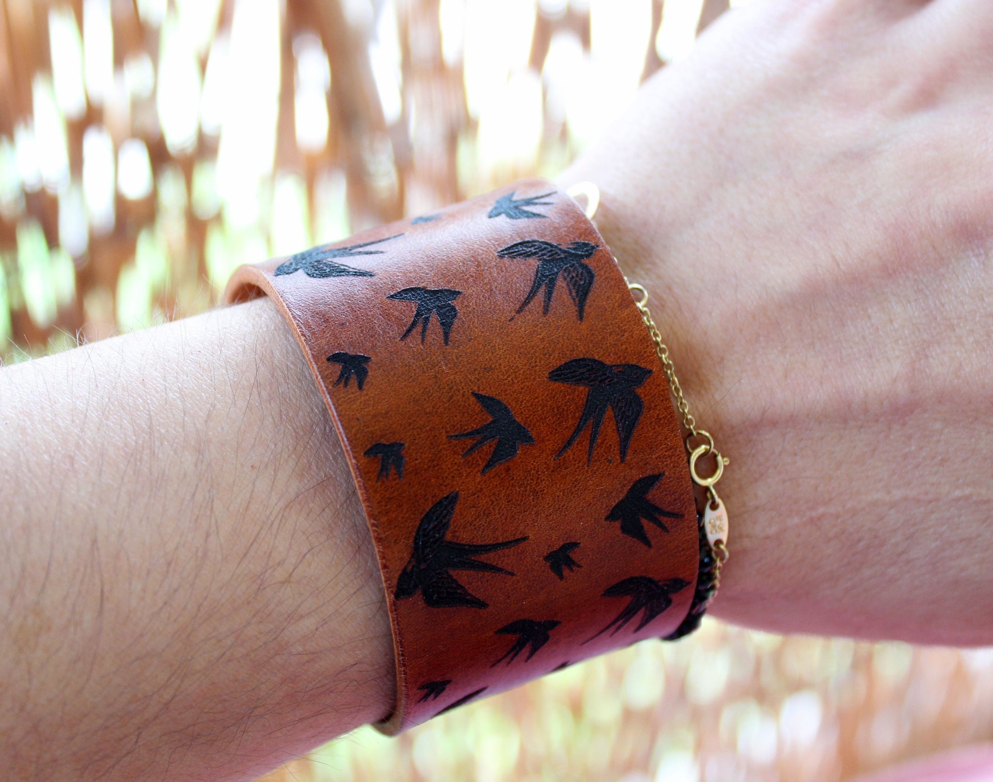 Flying Birds Wide Leather Cuff Bracelet worn on a wrist, showcasing its width and eye-catching design, adding joy and positive vibes to an outfit. Handmade by Lucky Seven Leather.