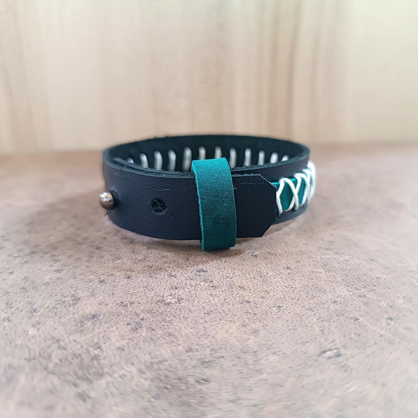 Navy Blue leather wrap bracelet with teal strap on a textured surface