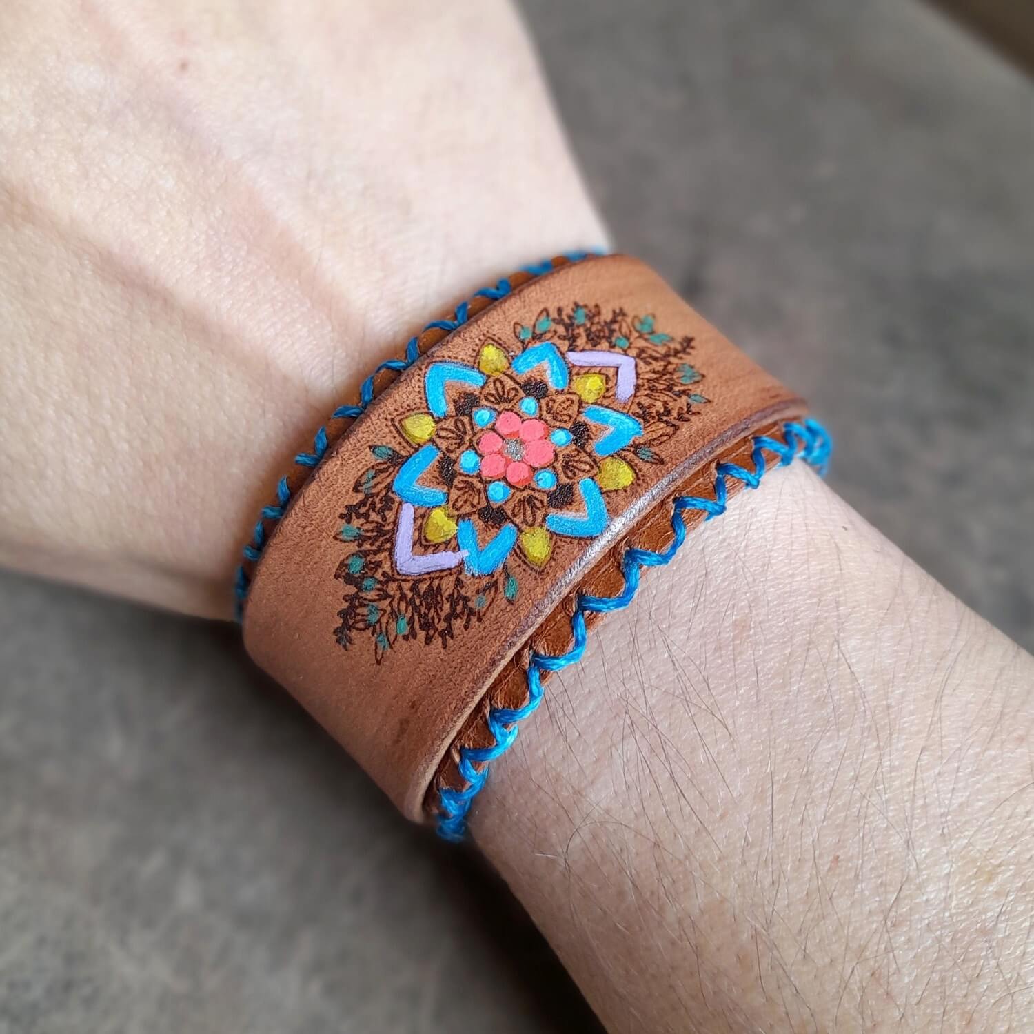 The Hand Painted Mandala Flower Leather Bracelet worn on a wrist, demonstrating its cute boho charm, comfortable fit, and how it brightens an outfit.