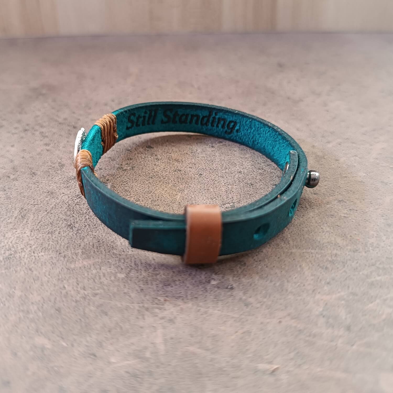 Inner Anchor Bracelet - Blue Lotus design. Handcrafted on petrol blue Crazy Horse leather, symbolizing healing and transformation - side view, showing secret engraved area reading "Still Standing".