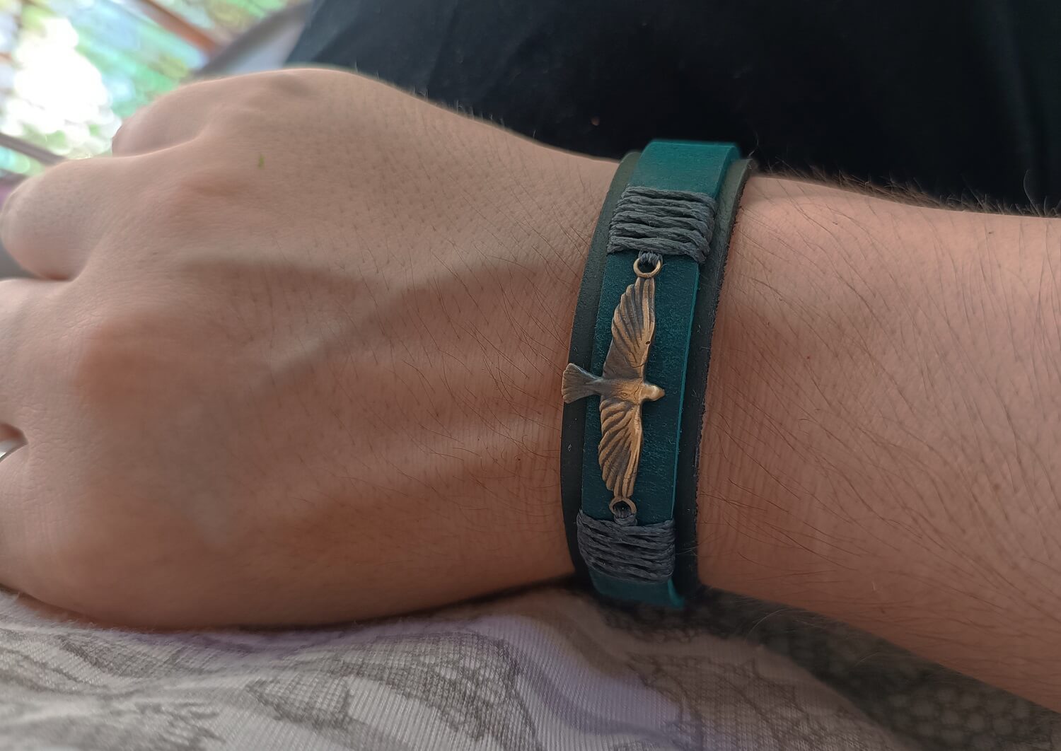 The Inzaghi Bracelet worn on a wrist, showing the elegant contrast between the muted black/green leather, petrol blue strip, and industrial gray cord wraps. It evokes the quiet strength and unwavering presence of a silent guardian watching from the shadows.