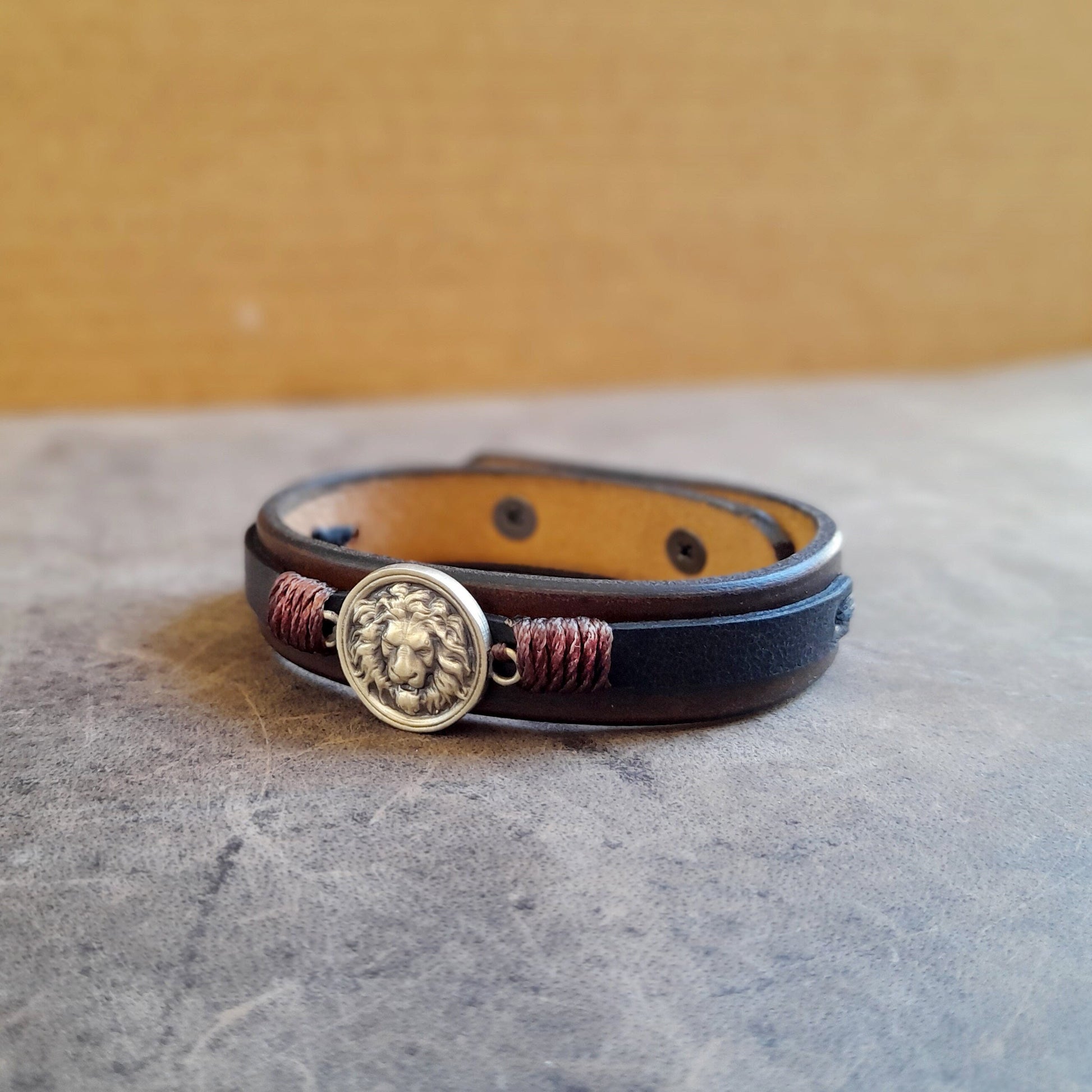 Lion Leather Bracelet. Handcrafted two-tone full-grain leather cuff in chestnut brown and black, with lion symbolism.