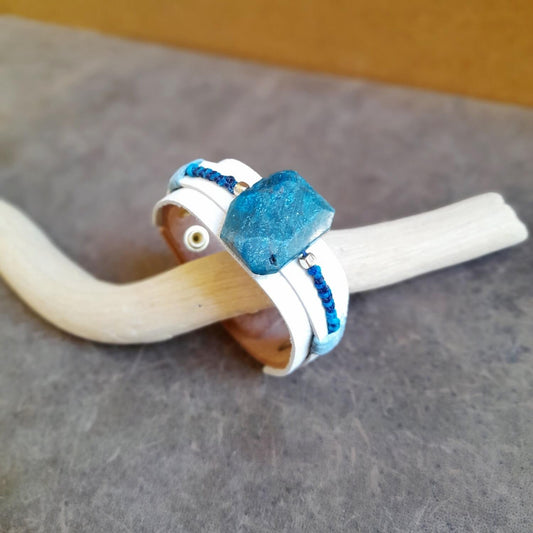 The OOAK Natural Raw Apatite White Leather Bracelet: A layered white leather cuff with gold metal beads and blue macramé, featuring a prominent large raw natural Apatite stone.