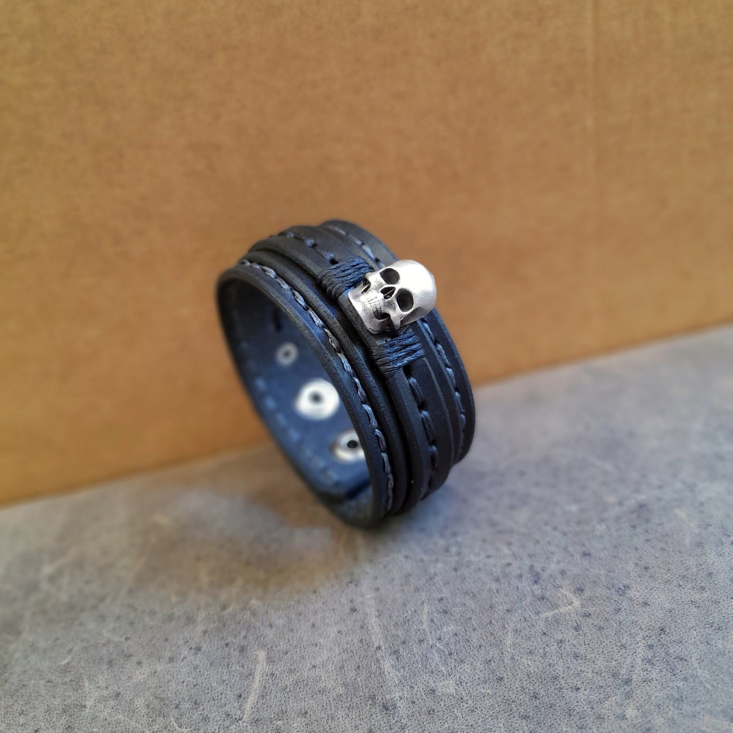 Men's black full-grain leather cuff with a prominent solid sterling silver 3D skull, side view , other angle