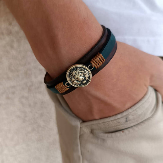Close-up of a person's wrist wearing a leather bracelet with a lion pendant