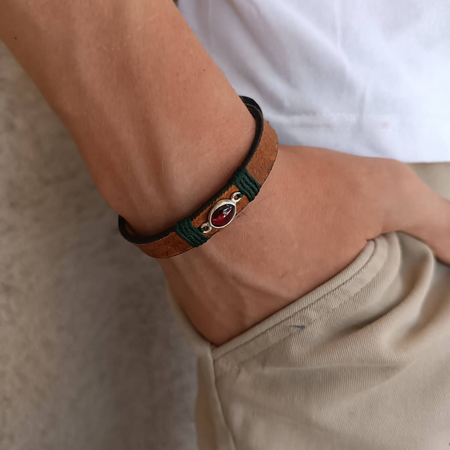 Minimal Red Garnet Leather Wrap Bracelet worn on a wrist, showcasing its adjustable fit and the subtle glow of the natural red garnet against the earthy brown leather. Handmade by Lucky Seven Leather.