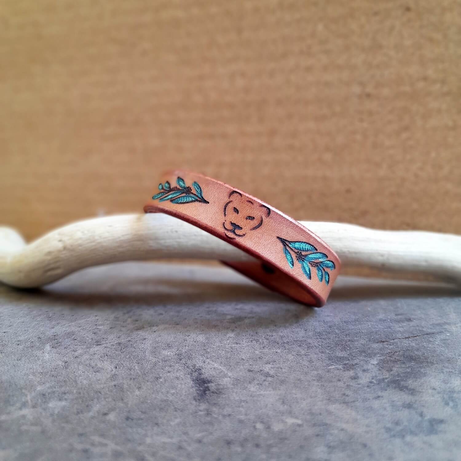 Minimalist Lioness Leather Bracelet, featuring the lioness head outline, hand-painted leaves, and soft earthy brown leather.