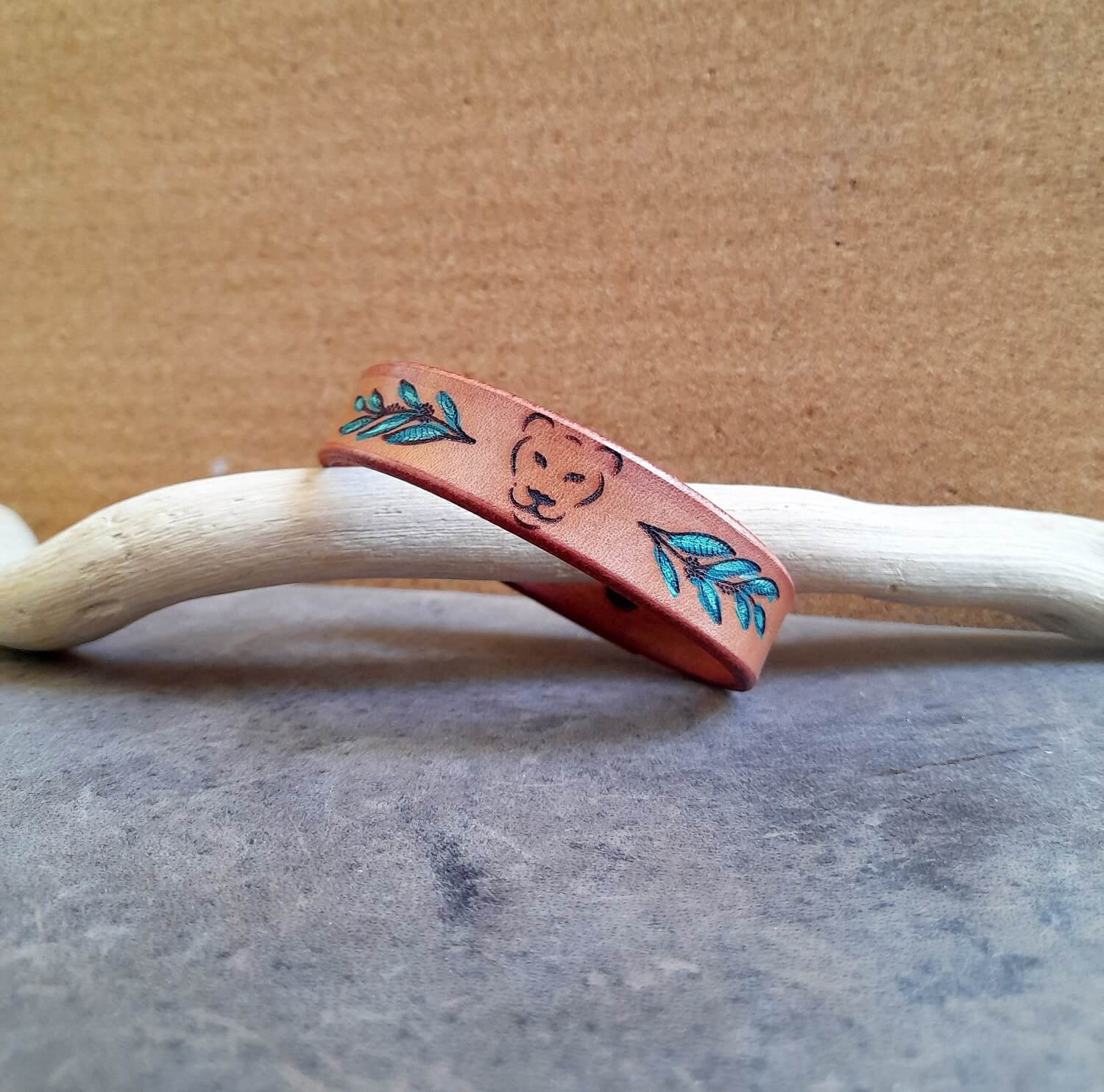 Minimalist Lioness Leather Bracelet, featuring the lioness head outline, hand-painted leaves, and soft earthy brown leather.