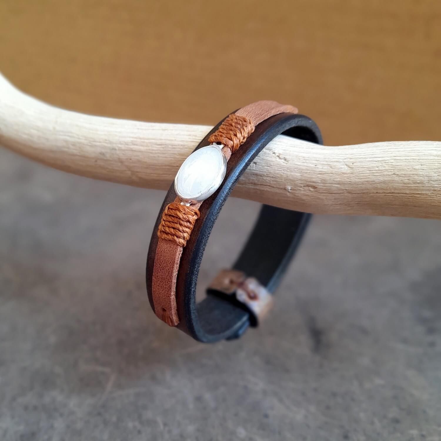 Close-up showing the chestnut brown bottom leather band and the earthy soil brown top layer on the Moonstone Glow Bracelet, with the warm brown waxed cord wrapping the pendant.