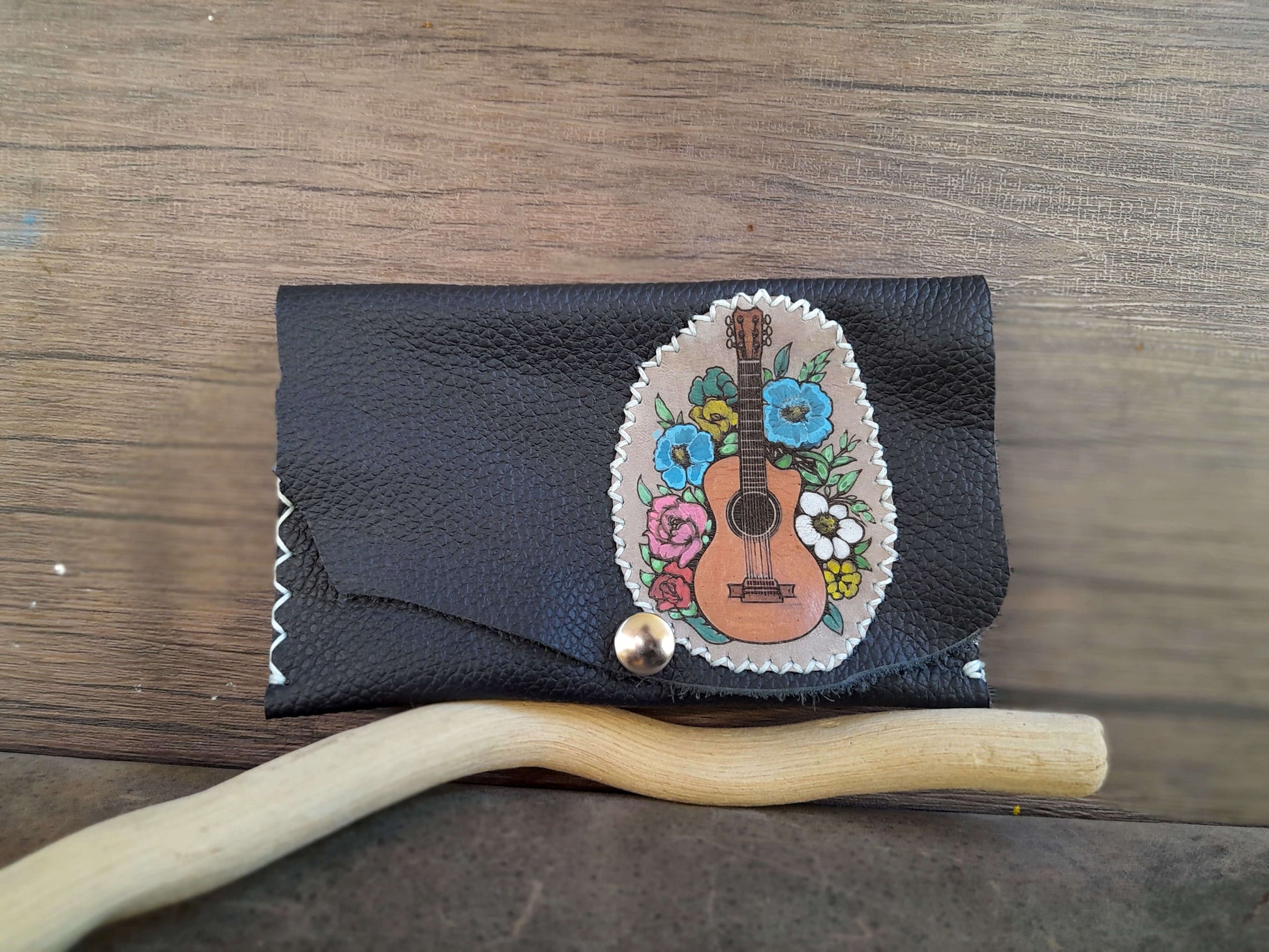 Navy Blue leather wallet with floral guitar design on a wooden surface