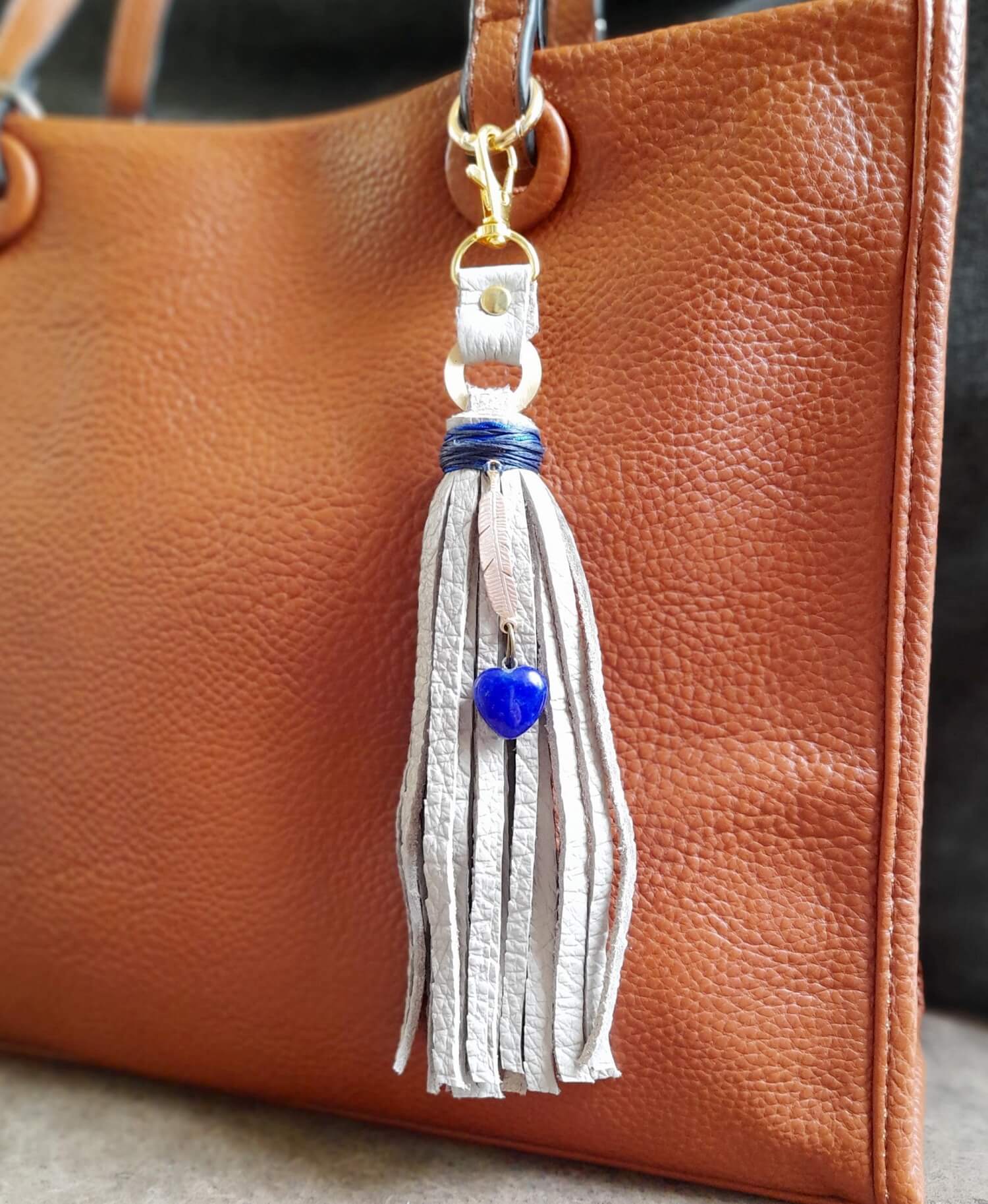 Tassel keychain with blue bead attached to a brown leather bag.