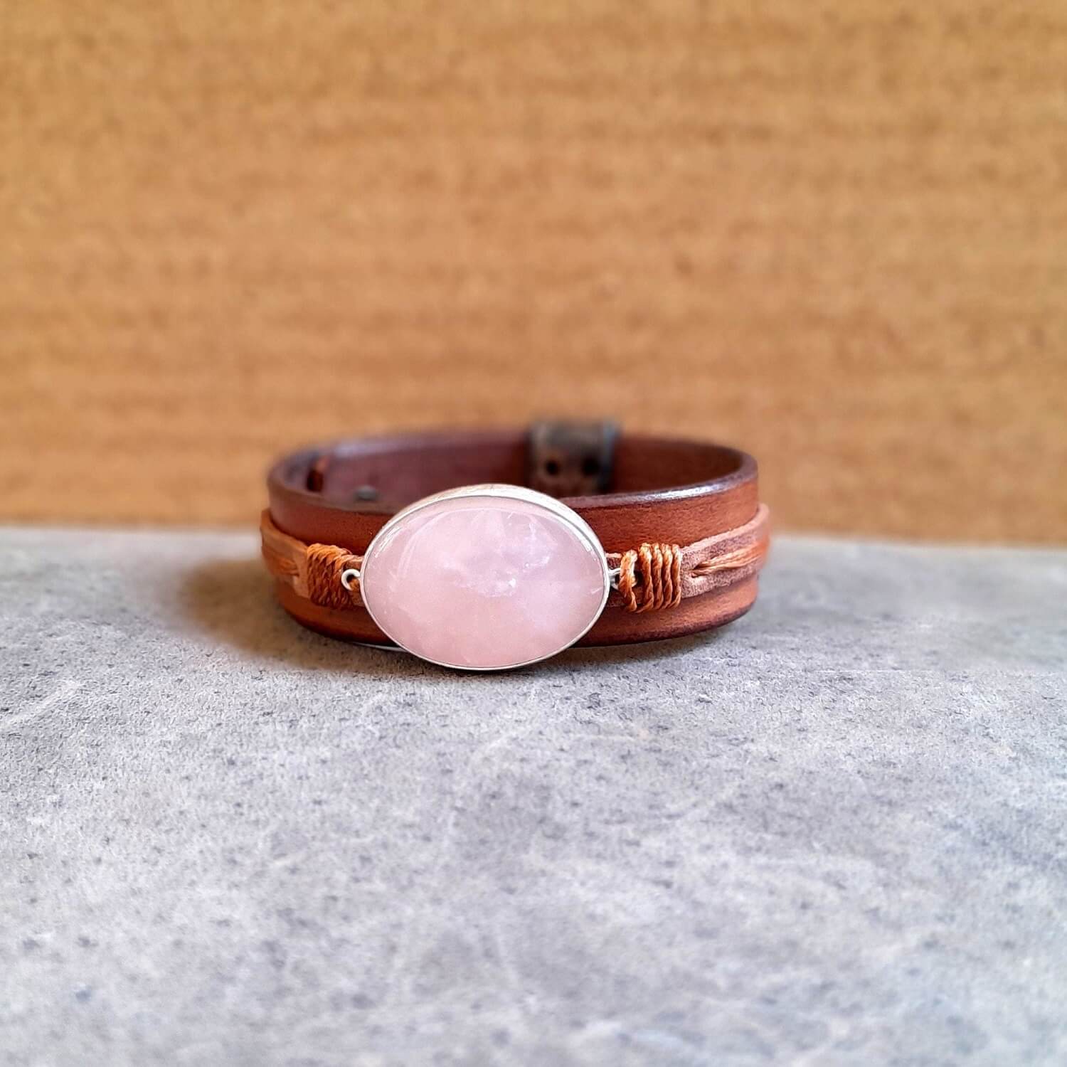The OOAK Large Rose Quartz Leather Cuff: A wide, layered oiled Vachetta and brown cowhide leather bracelet featuring a prominent oval natural rose quartz stone set horizontally on a sterling silver pendant, wrapped with warm brown cord.