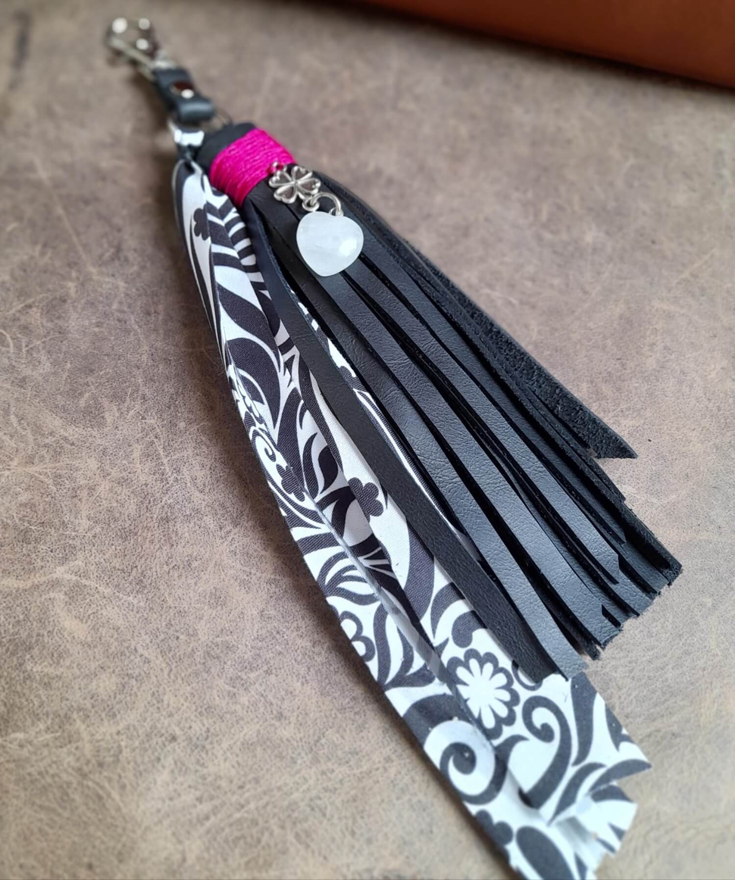 Detailed close-up of the natural Moonstone heart pendant and the stainless steel four-leaf clover charm on the black leather tassel, highlighting the stone's shimmer.