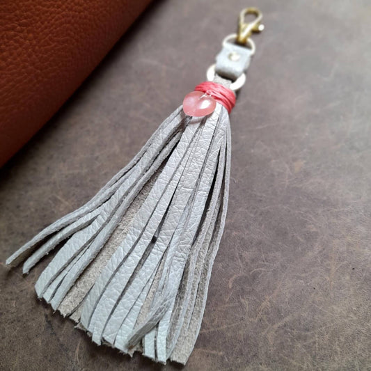 OOAK Rose Quartz Heart Charm with a gray leather tassel. Features a genuine Rose Quartz heart pendant wrapped with bright pink thread. Comes with a brass gold-tone O-ring and lobster clasp.