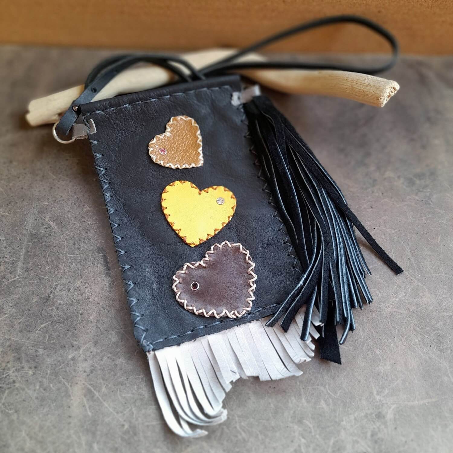 Hand-cut and hand-stitched leather phone bag in dark brown sheepskin with applied leather hearts and a long black suede tassel.