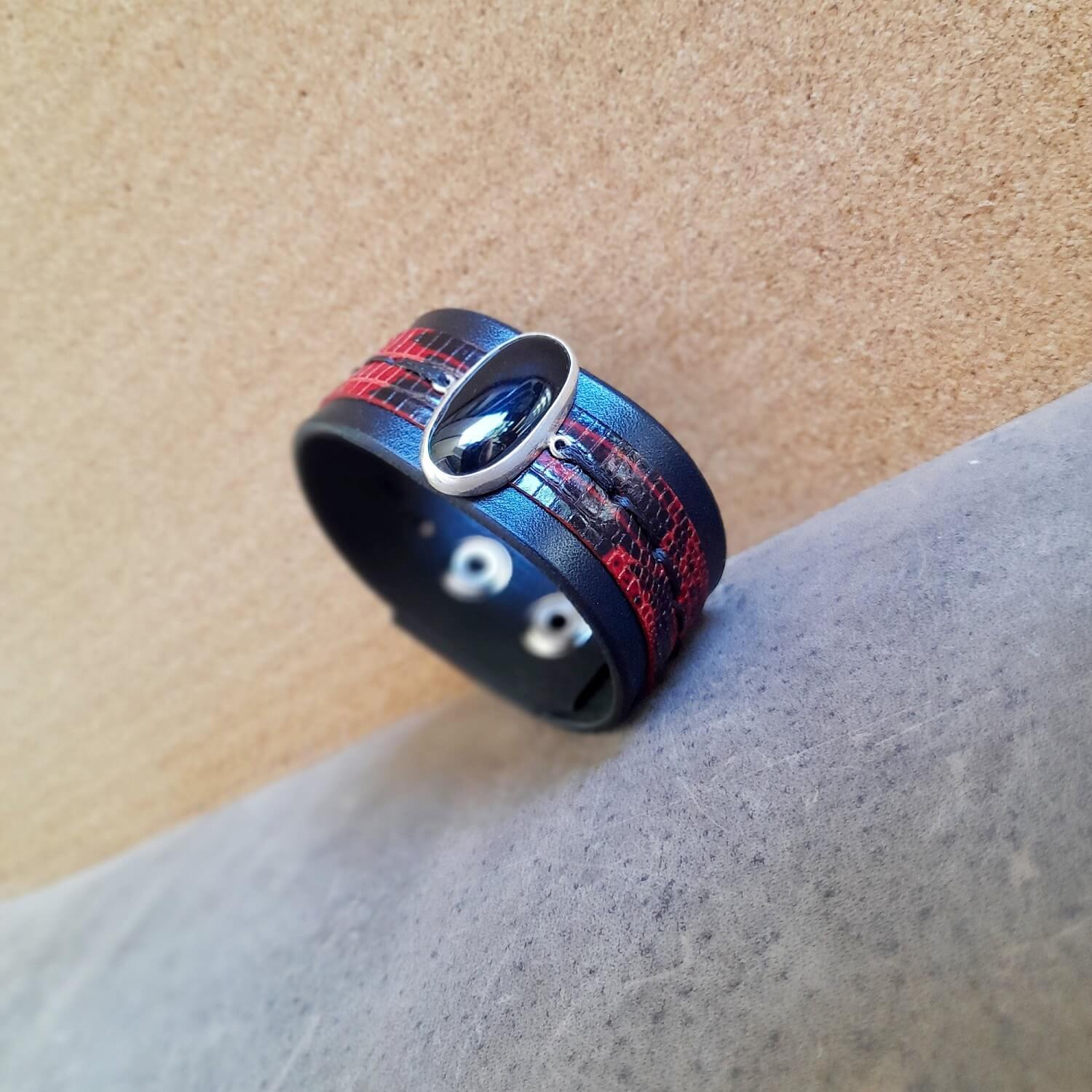 Wide black leather bracelet with a sterling silver pendant featuring a large oval black obsidian stone and black and red reptile skin accent.